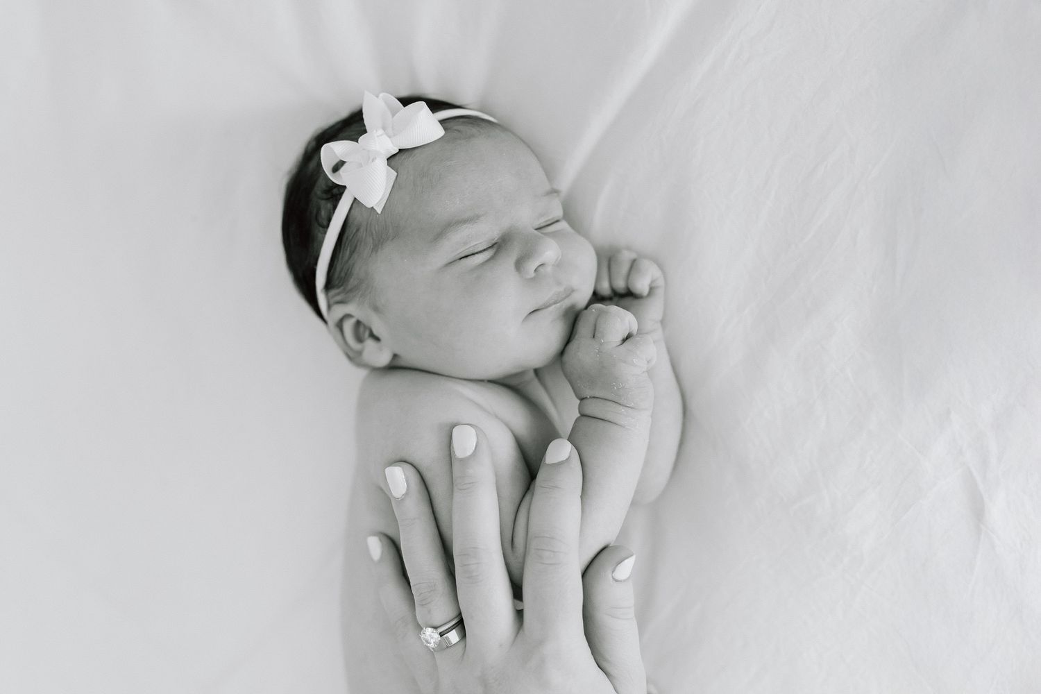 Black and white photo series of a sleeping newborn baby in various peaceful poses on soft blankets.