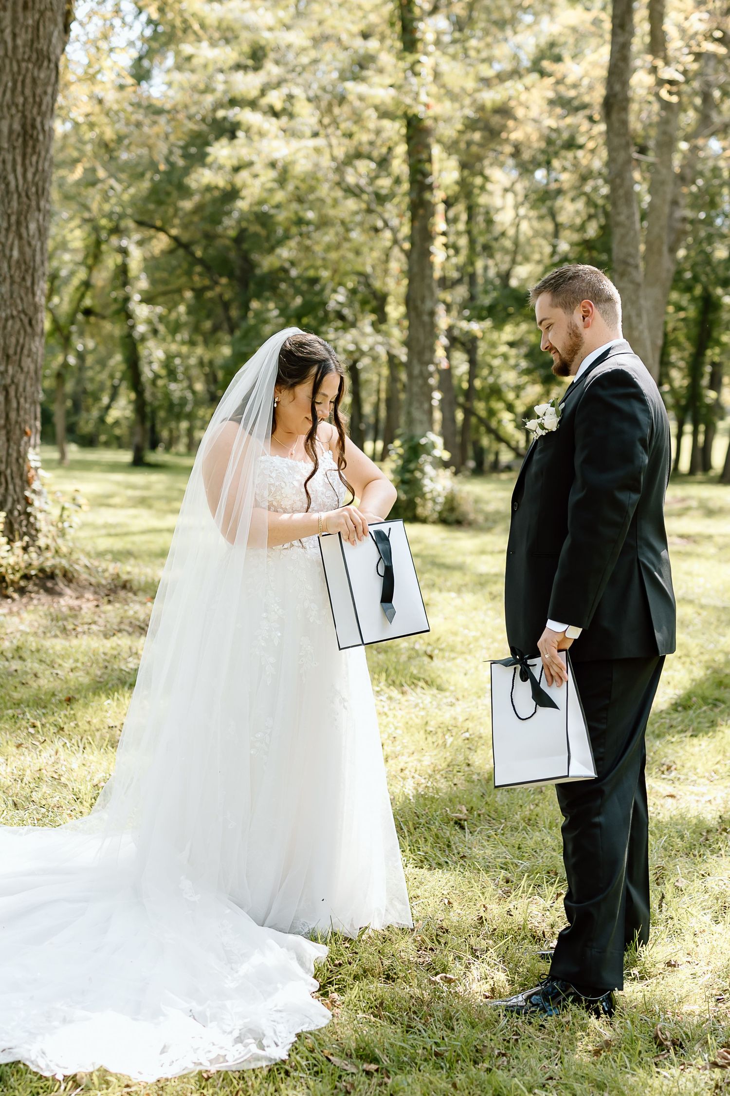 A couple shares an intimate first look moment in a sunlit forest setting during their wedding day.