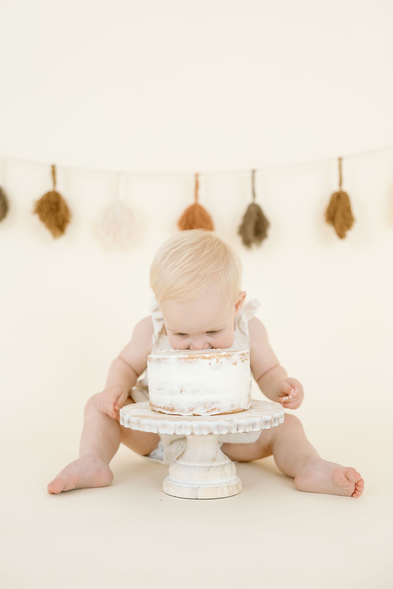 Three sequential photos show a baby diving face first into a white birthday cake on a light background with leaf decorations.