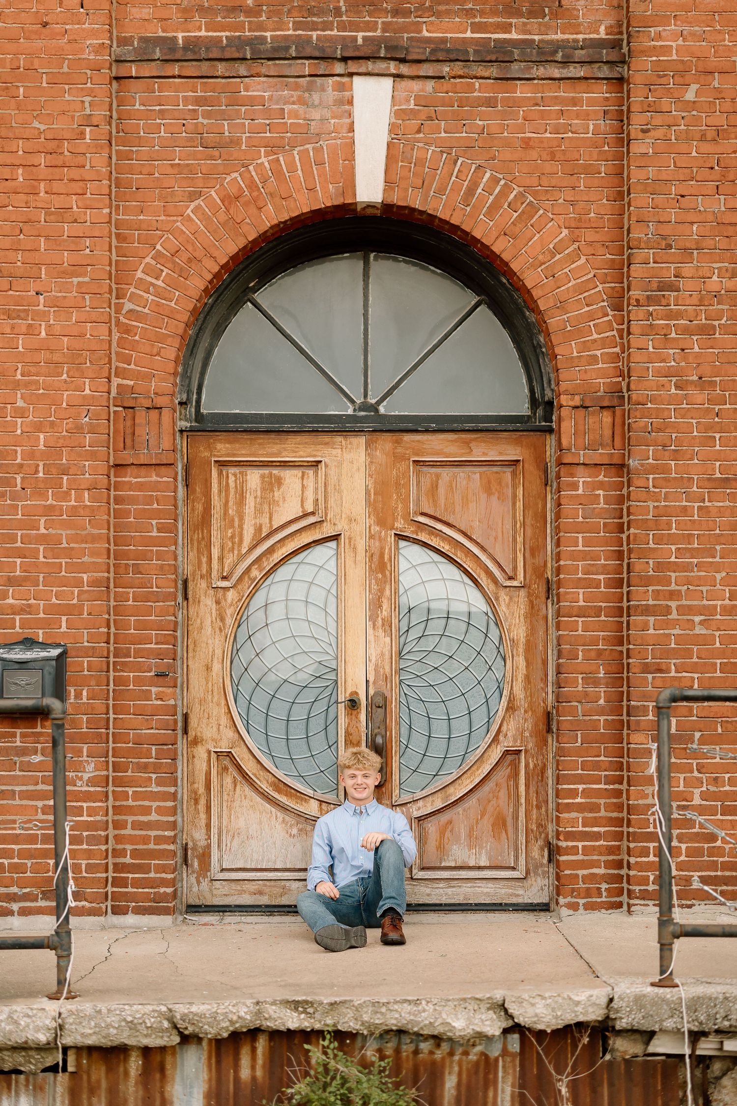 Three vintage wooden doors with circular glass designs in a rustic red brick building facade.