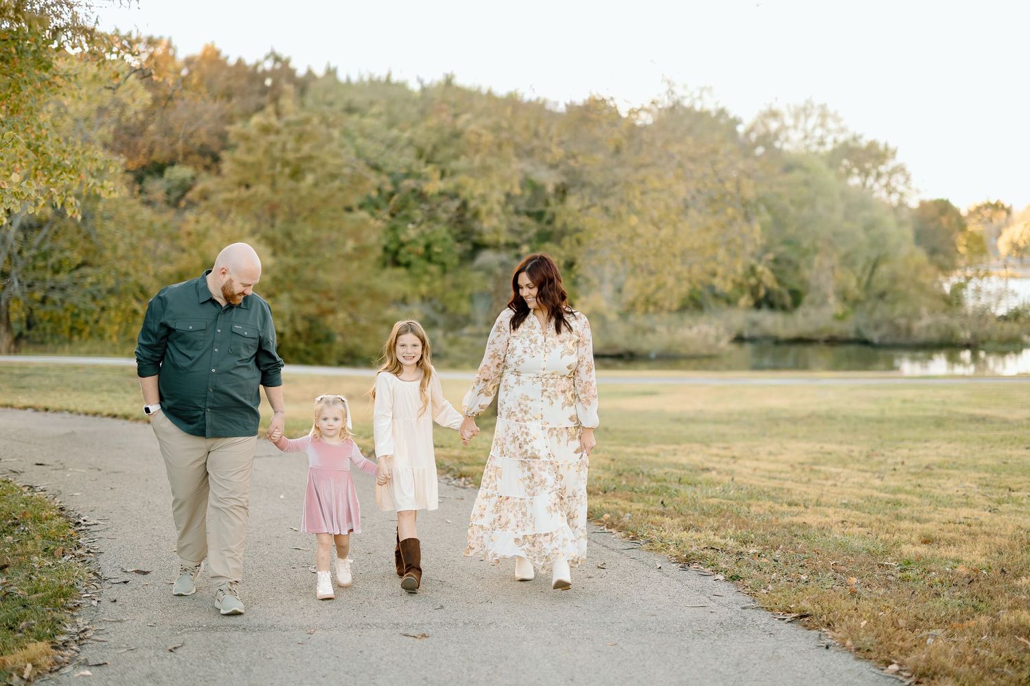 A family walks together through a scenic autumn park during golden hour sunset.