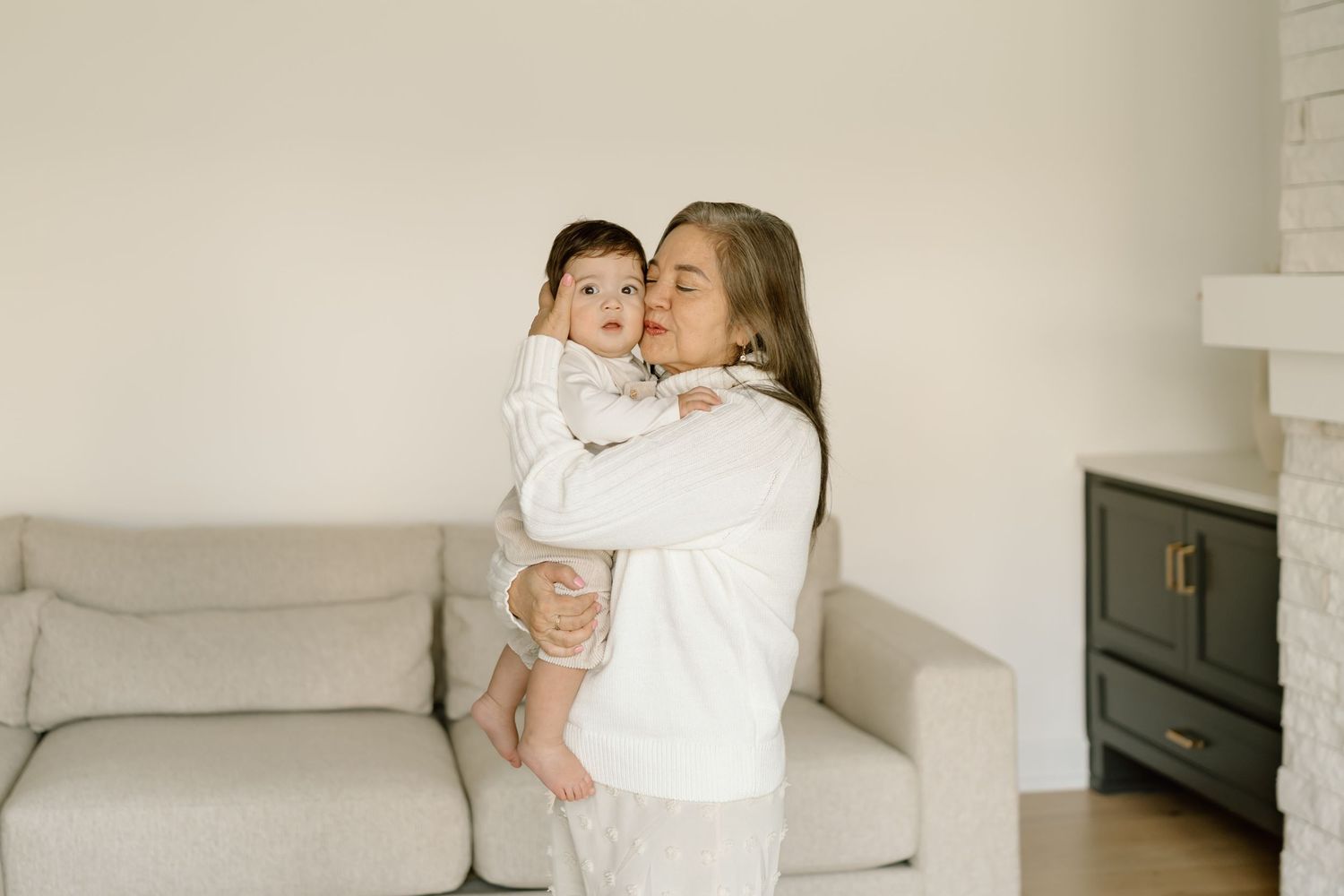 A series of five minimalist family portraits against white walls showing tender moments between parents and children.