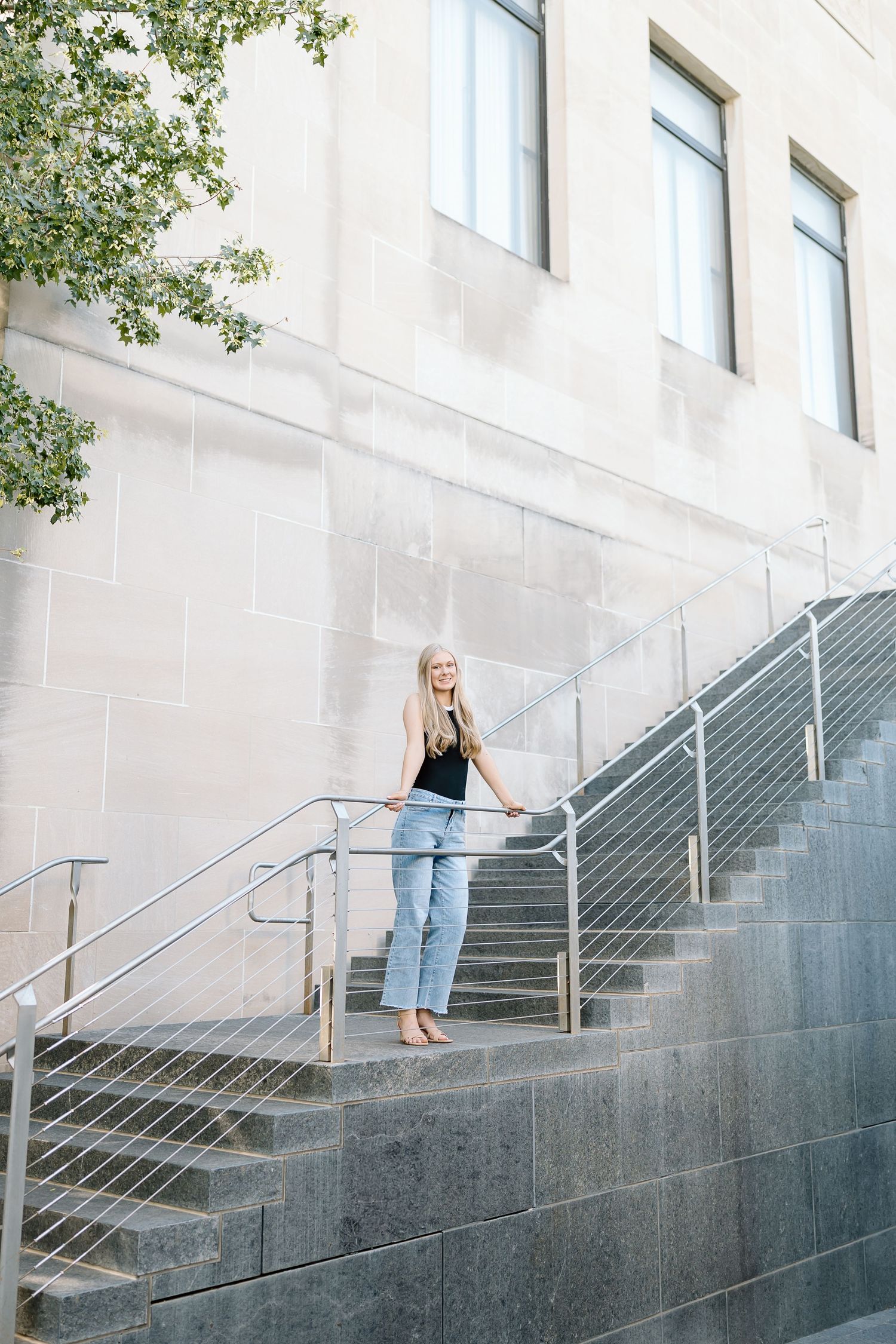 A person in light jeans and black top descends concrete stairs with metal railings in a multi-frame sequence.
