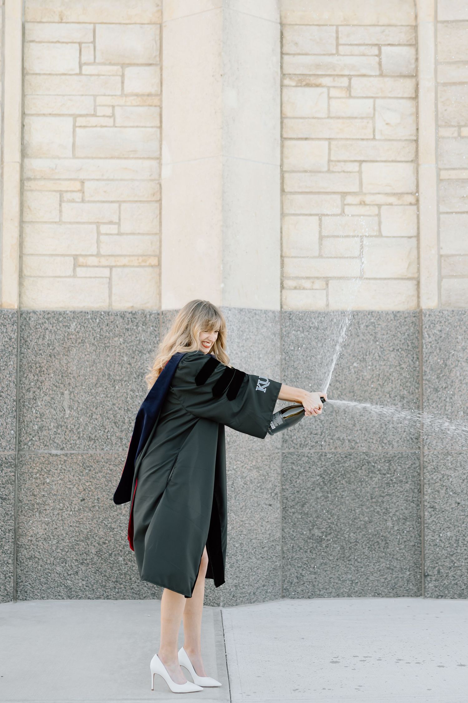 A sequence of four photos shows someone in a dark coat bending over while wearing white heels against a stone wall.