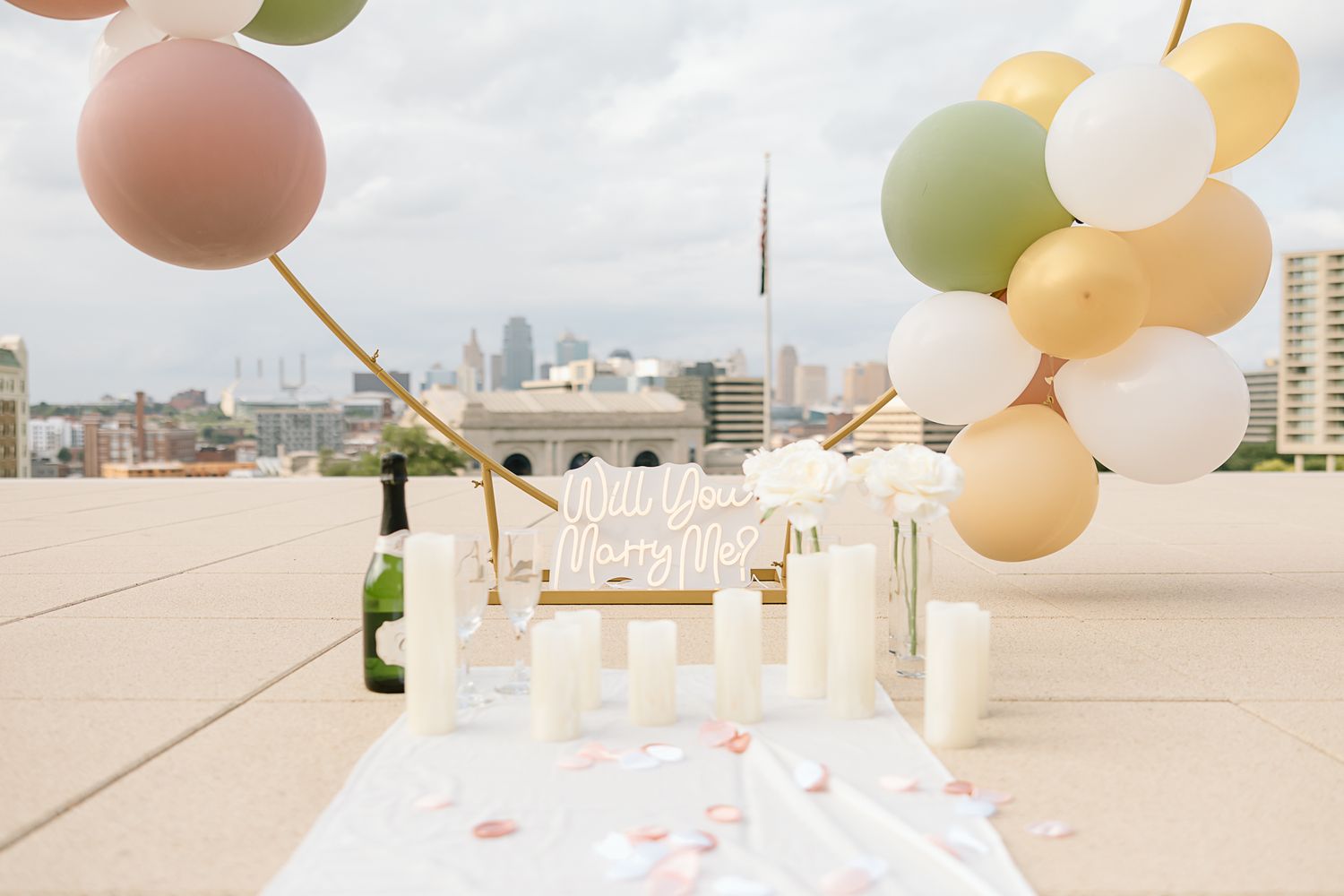 Elegant rooftop party setup with white and peach balloons against a city skyline backdrop.