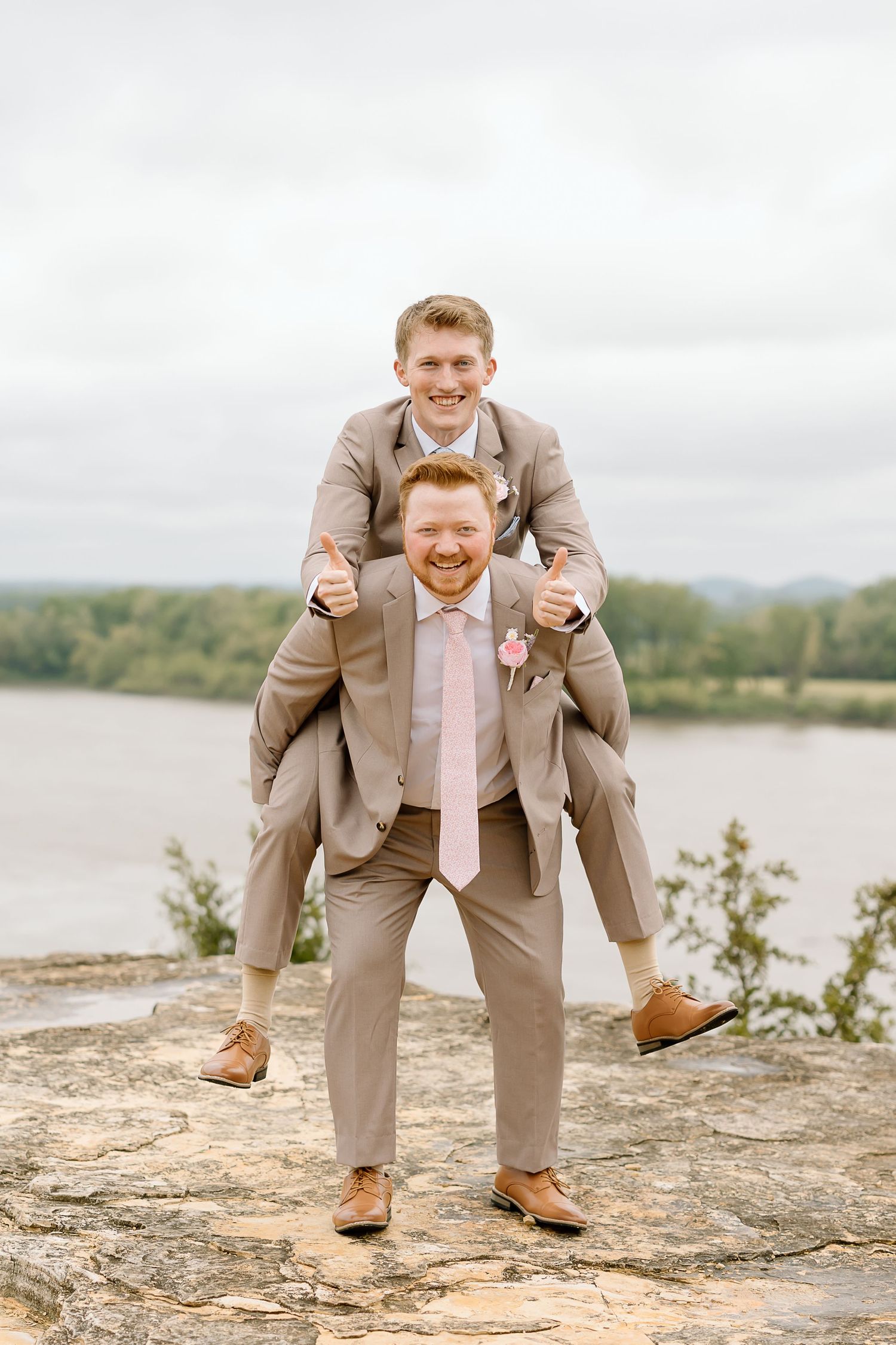 Three sequential photos show someone in a beige suit striking playful poses on a rocky ledge near a lake.