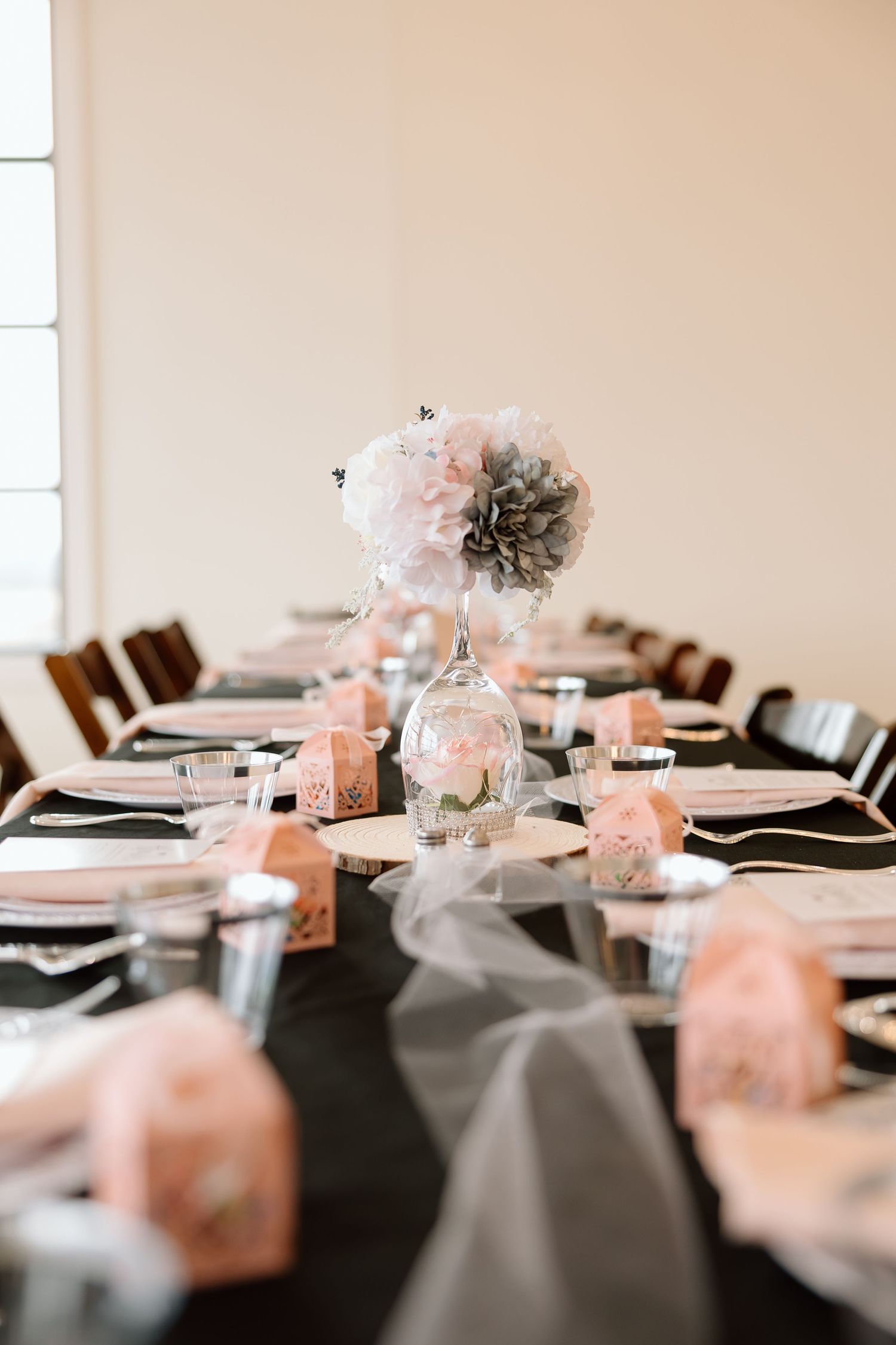 Elegant table setting with pink and gray decorations featuring tissue paper poms and place settings for a formal event.