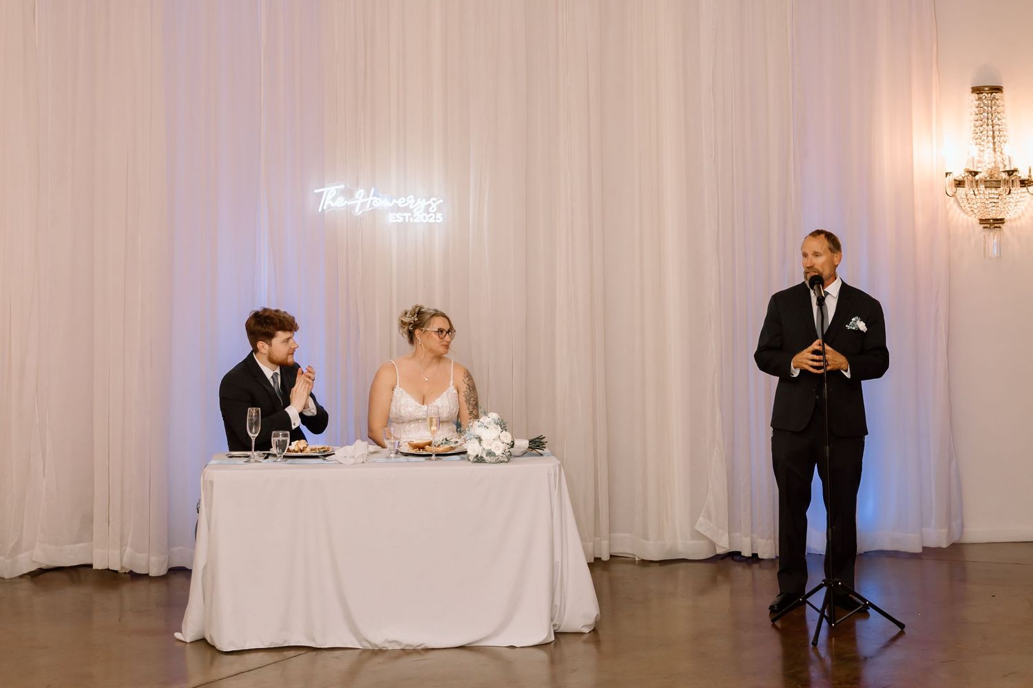 Wedding reception venue with white drapes and crystal chandeliers creates an elegant atmosphere.