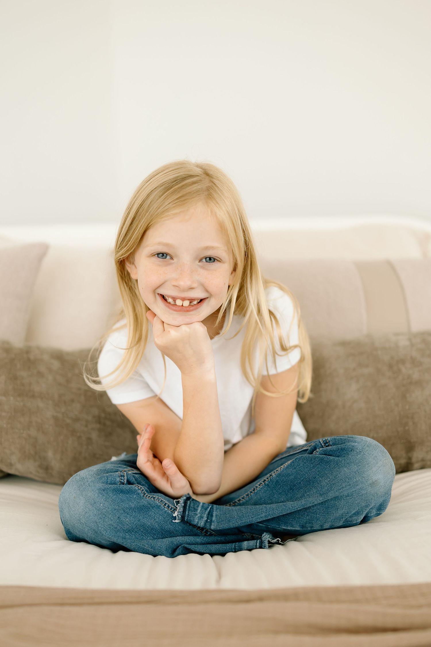A series of three candid lifestyle photos showing a child in white shirt and jeans relaxing on a beige couch.