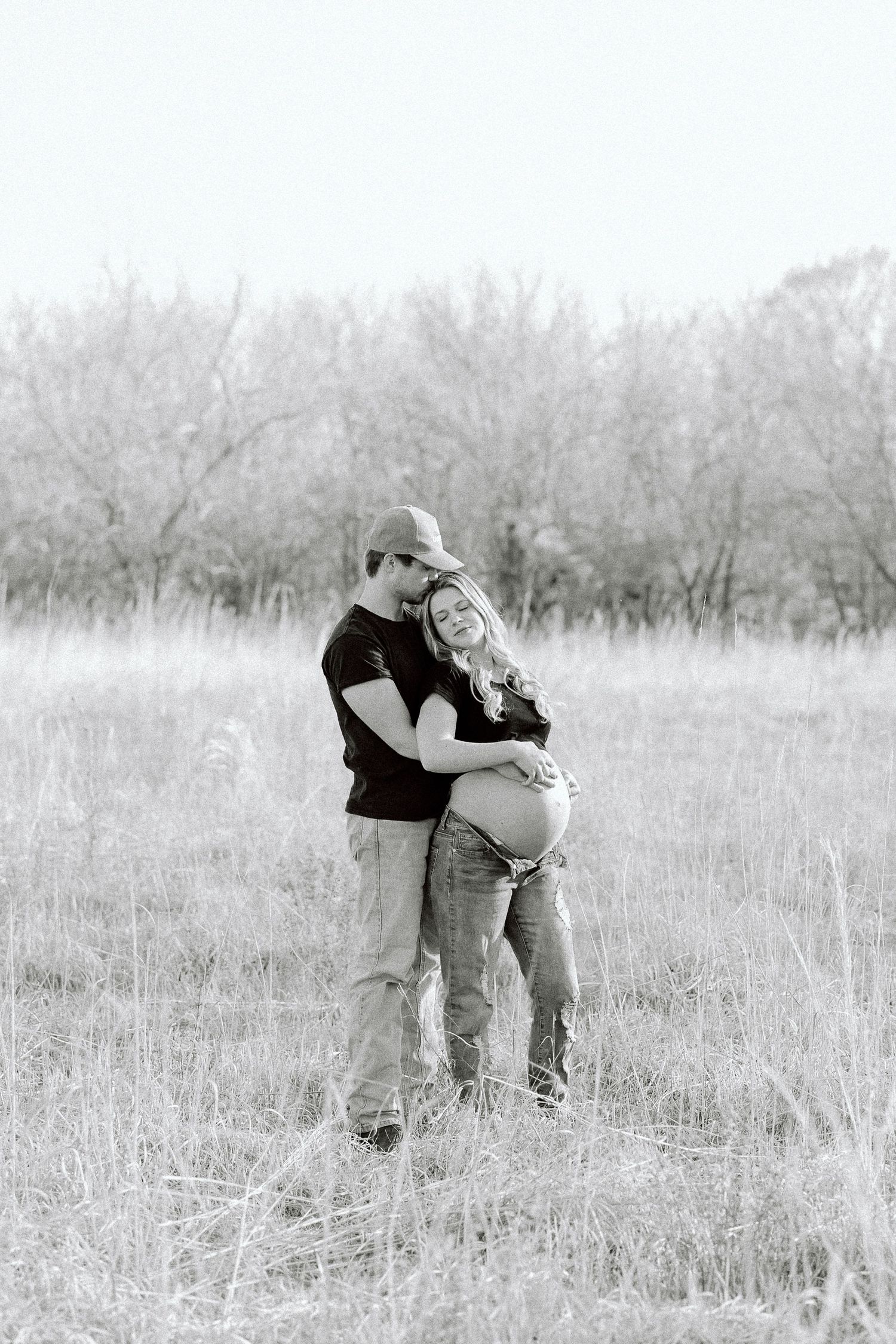 A sequence of black and white photos showing a playful couple embracing in a misty field of tall grass.