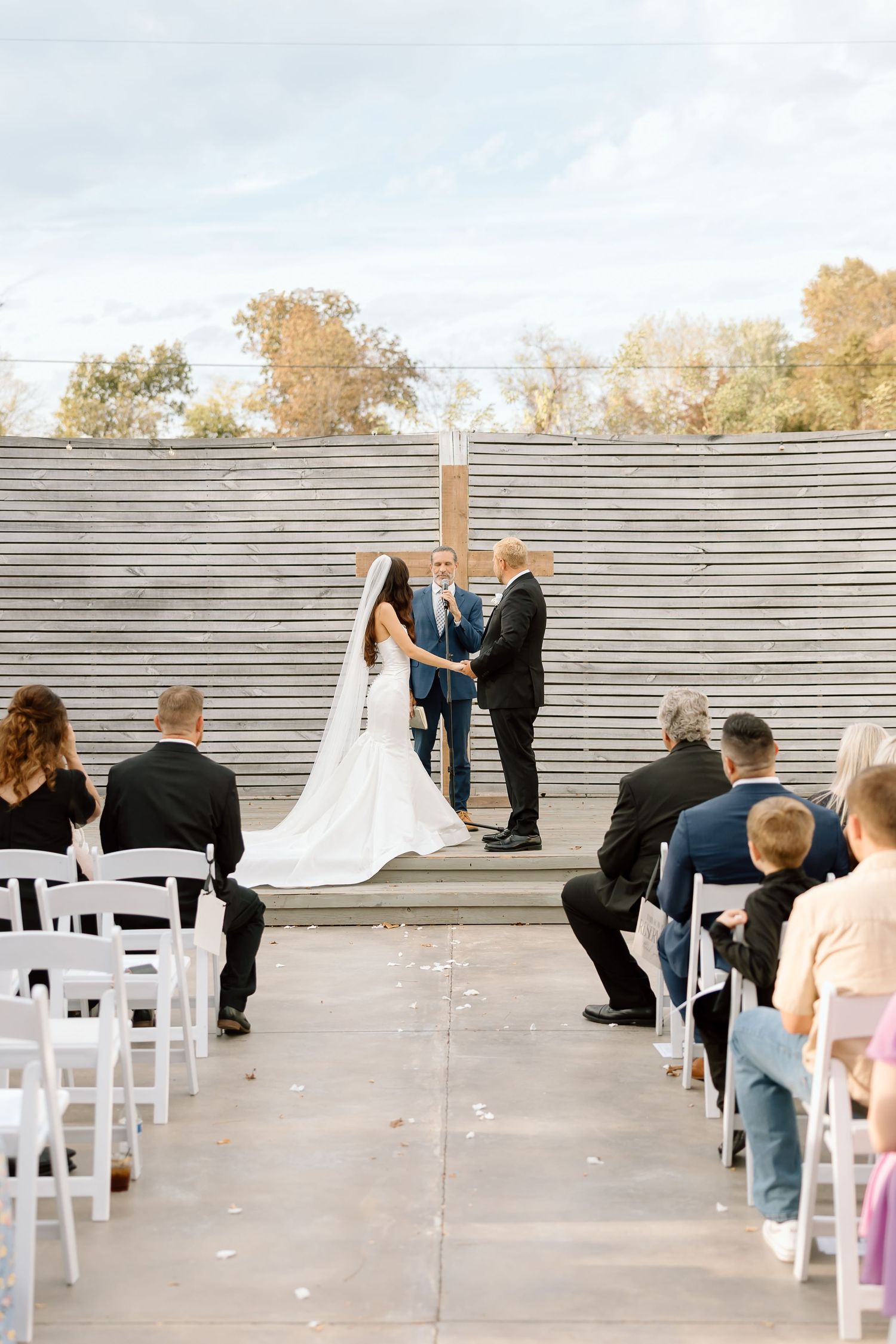 A panoramic view of an outdoor wedding ceremony setup with white chairs arranged in rows on concrete steps.