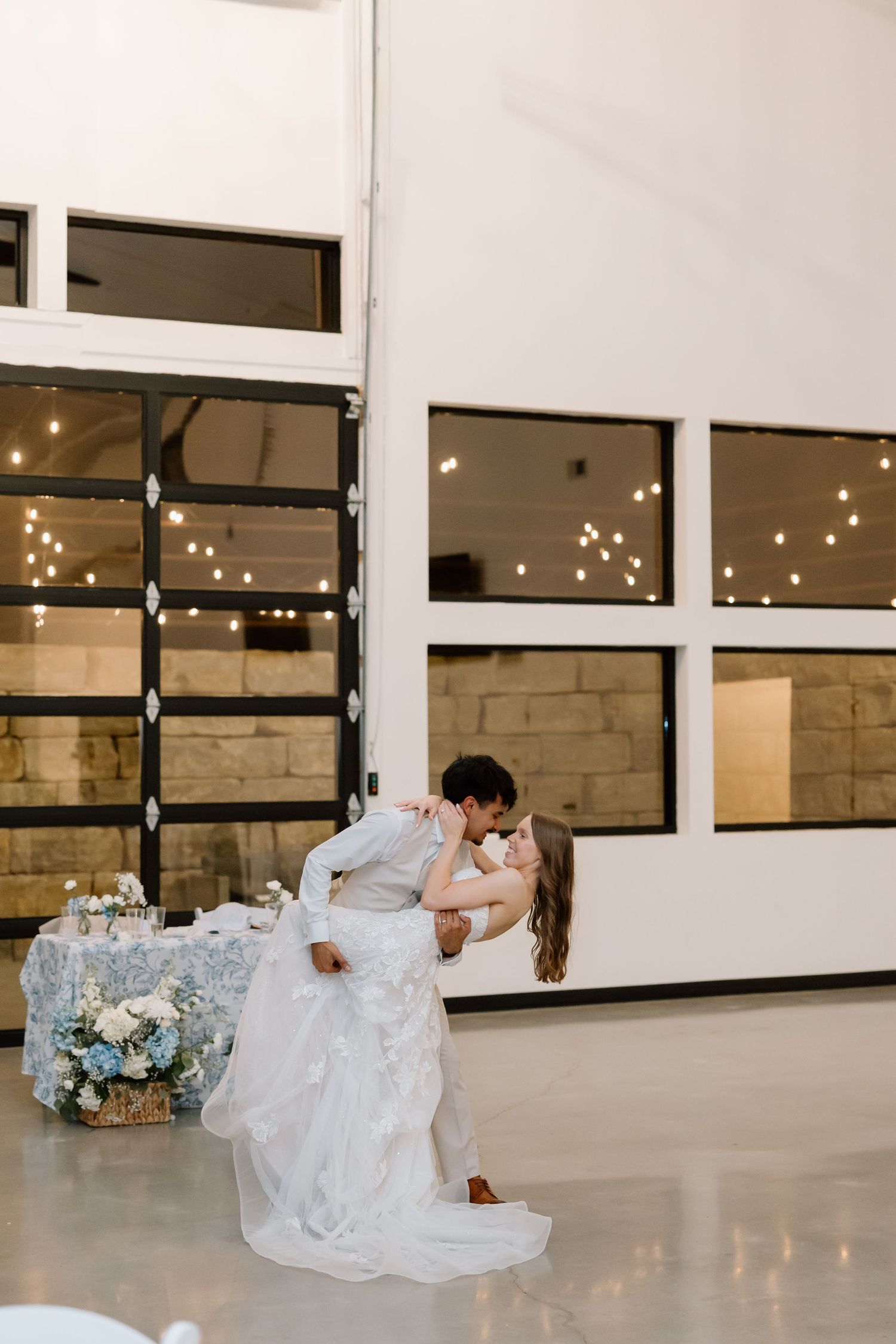 Bride and groom share a romantic dip kiss on the dance floor at an elegant wedding reception venue.