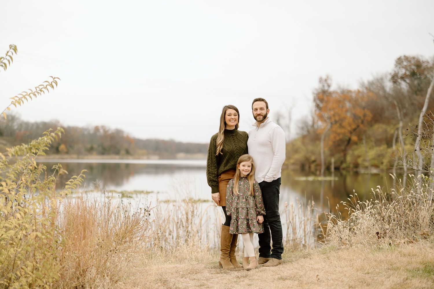 Autumn family photoshoot by the waterfront with tall grass and fall colors.