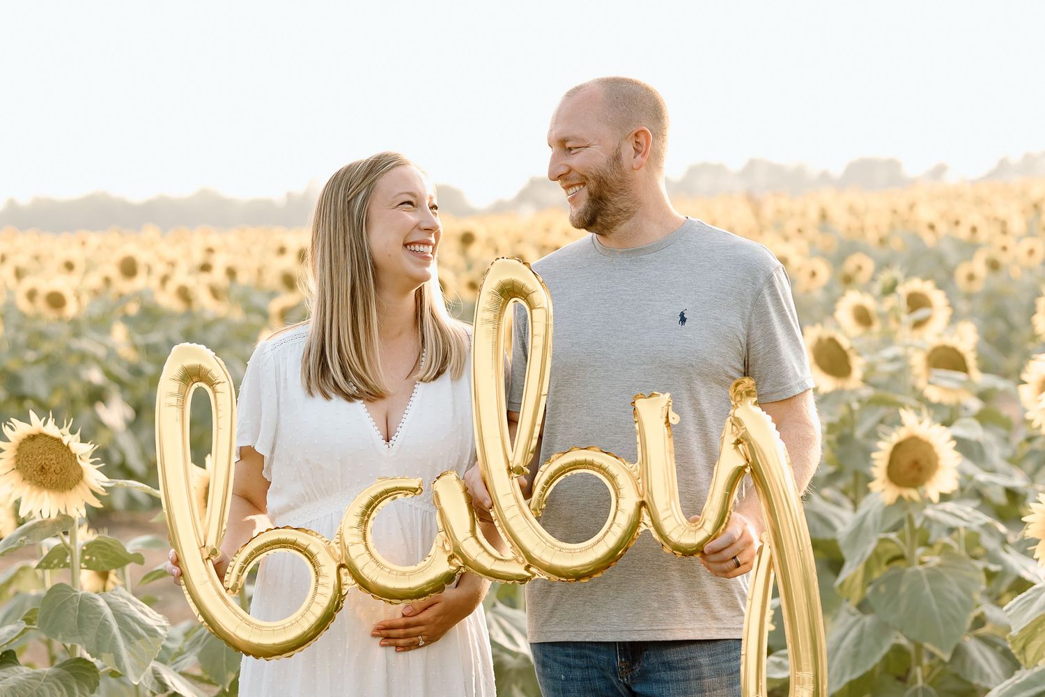 A couple shares a joyful moment together in a golden sunflower field at sunset.