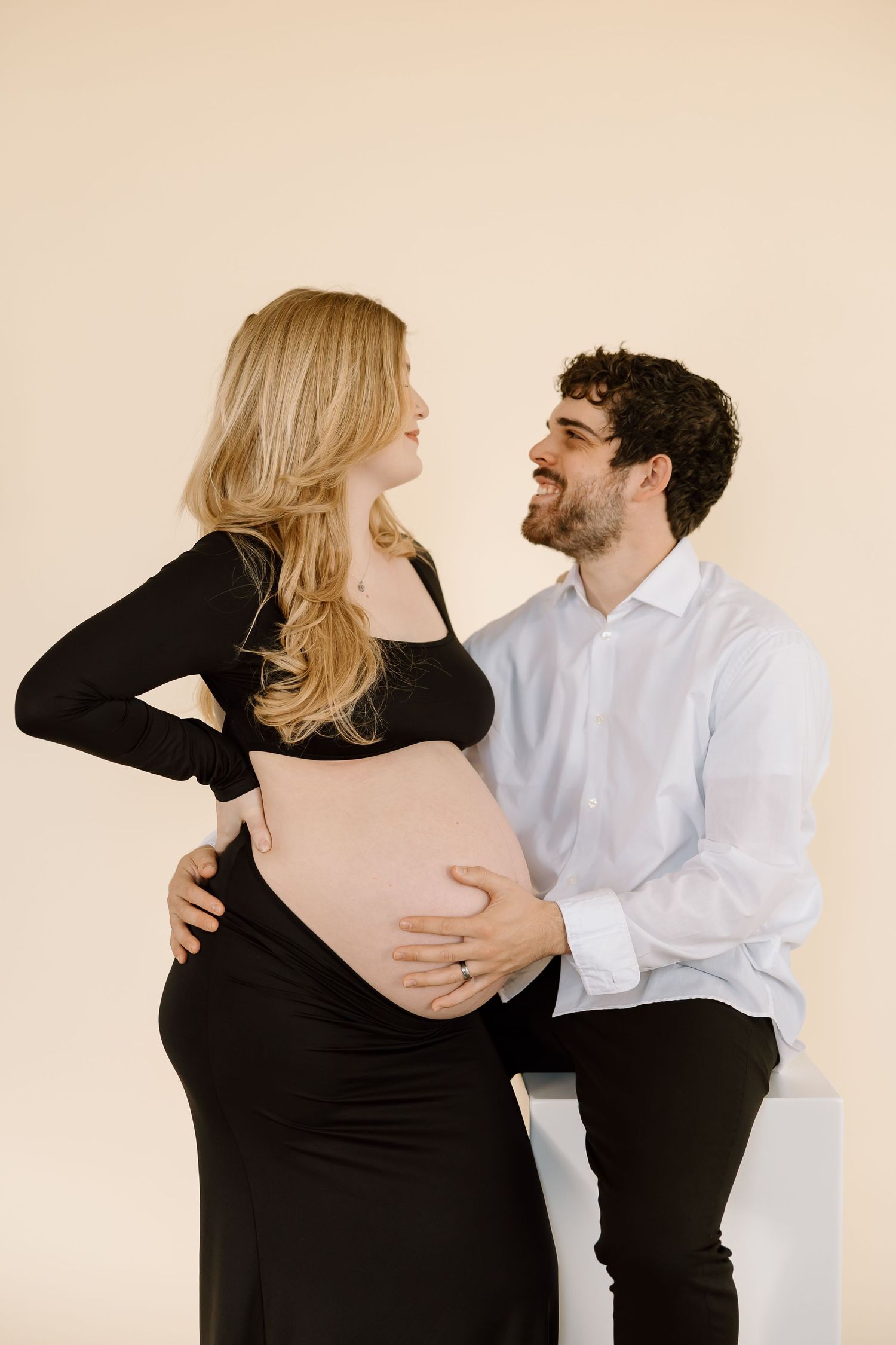 Joyful maternity moment captured as couple shares loving glance.