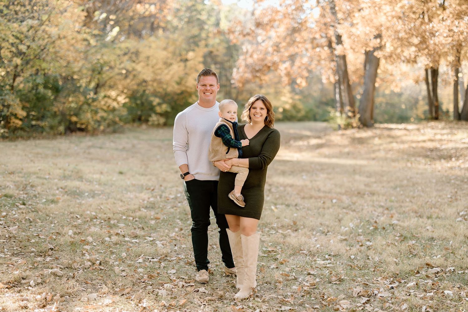Casual family portrait in outdoor setting with fall foliage backdrop.