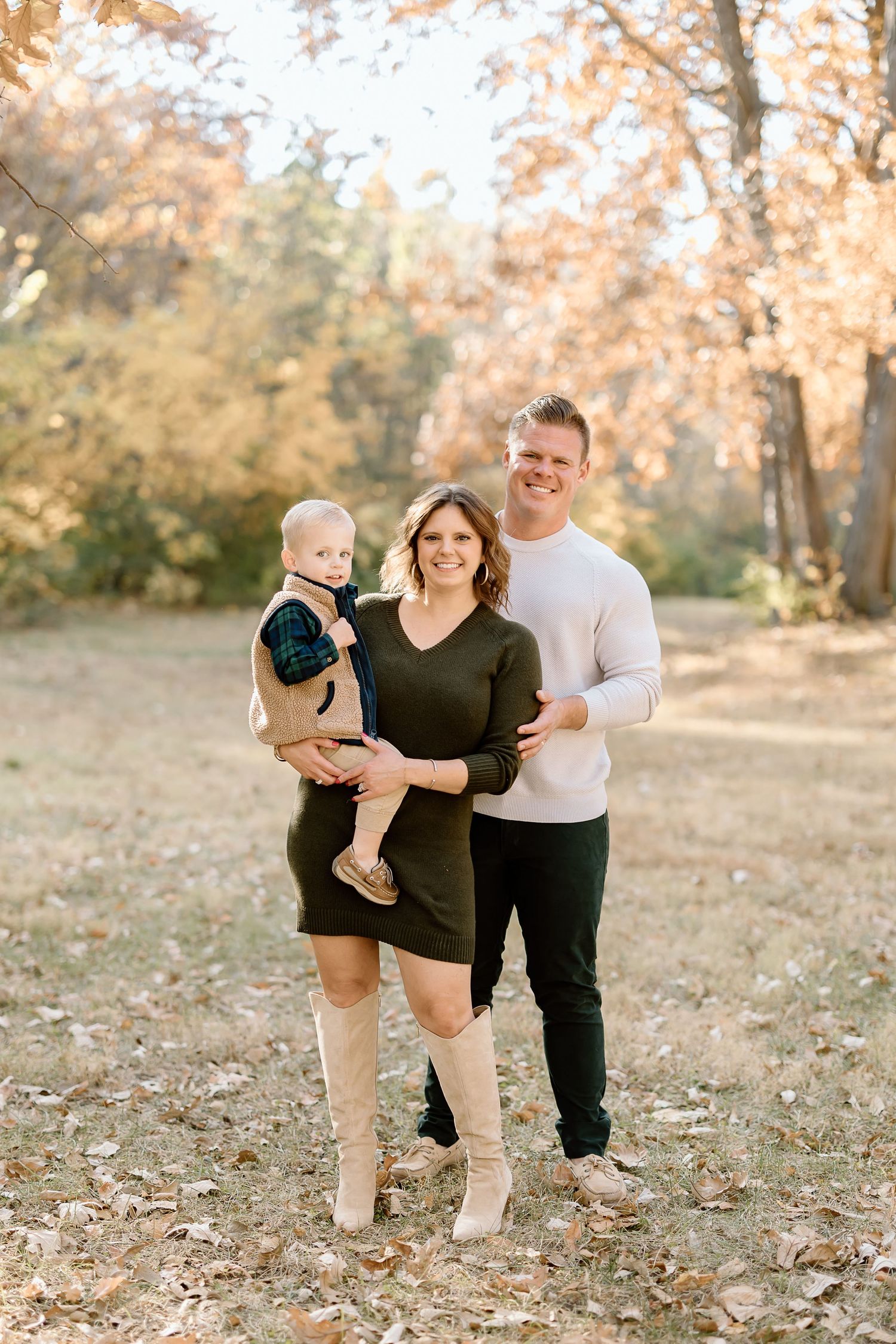 Family outdoors during fall season with golden leaves in background.