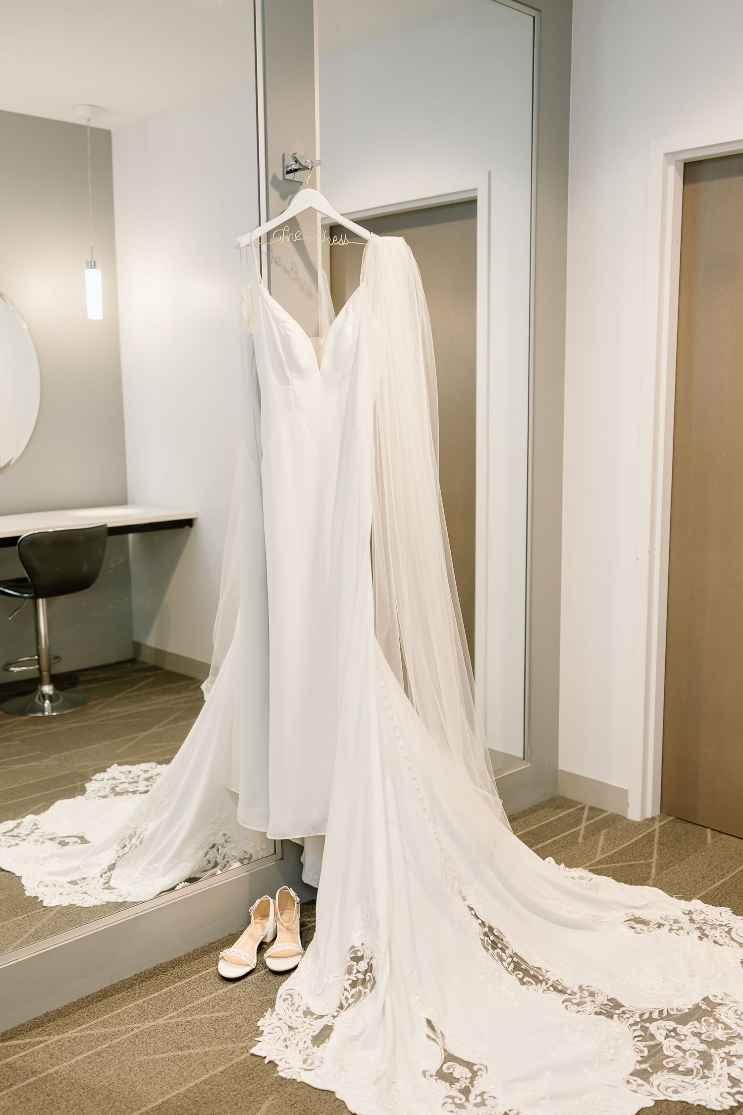 Long white cathedral-length wedding dress train with intricate lace detailing extends across a sleek tiled floor.