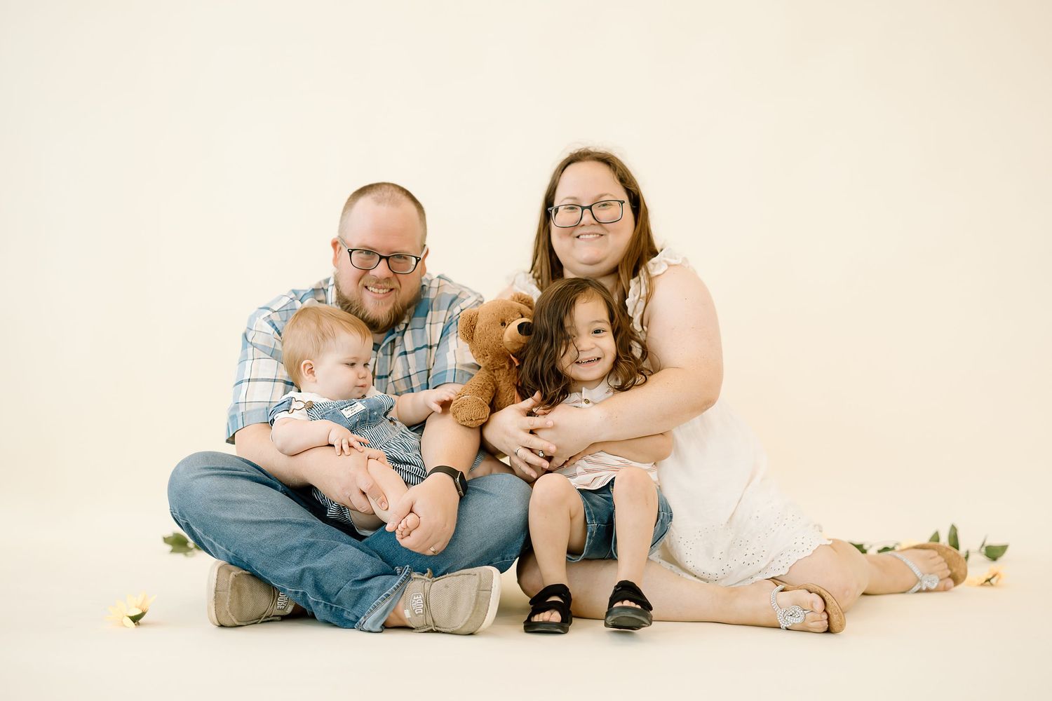 A family relaxes together on a white backdrop in coordinating blue and white outfits for a portrait session.