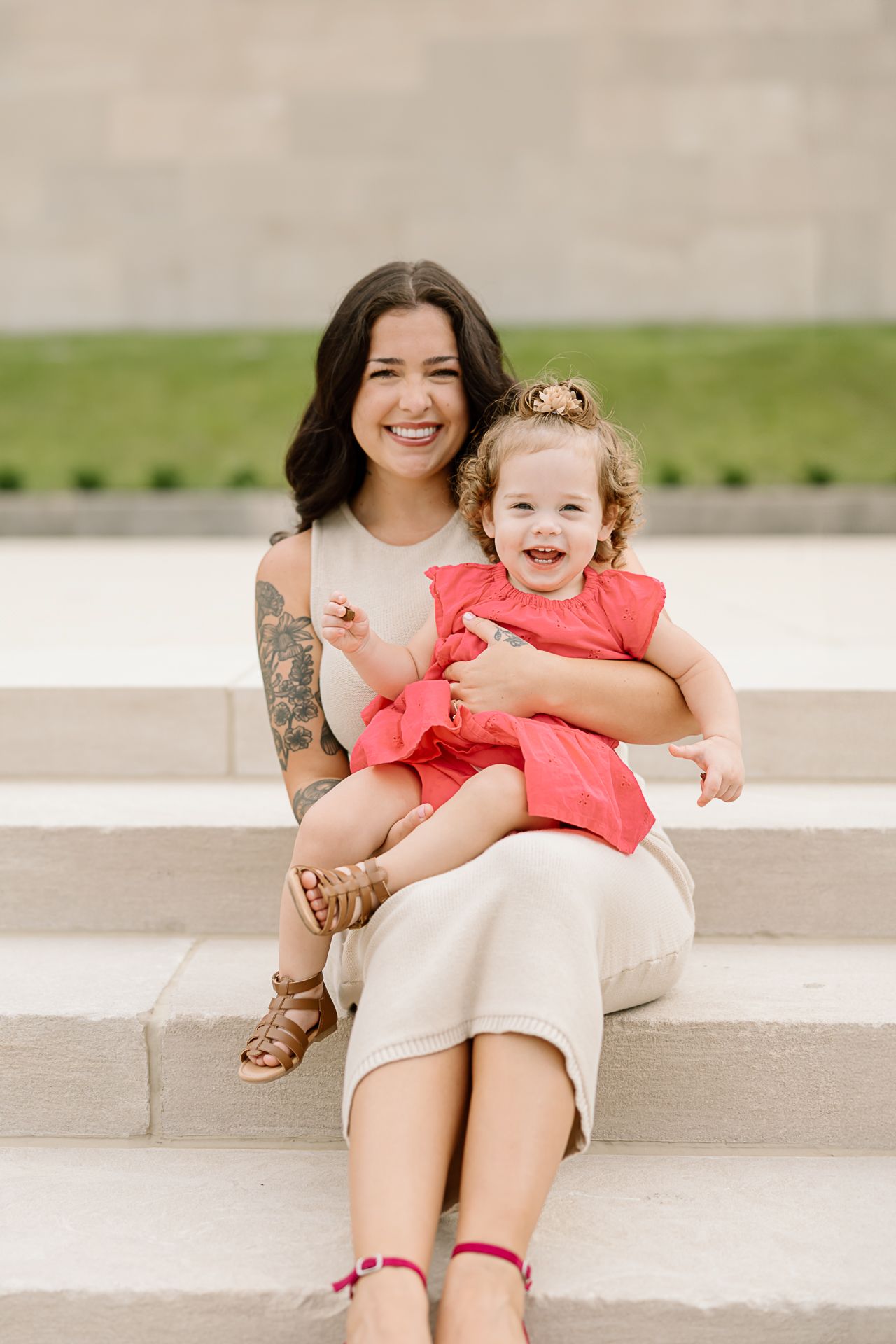 Mother and child sharing joyful moments while sitting on concrete steps outdoors.