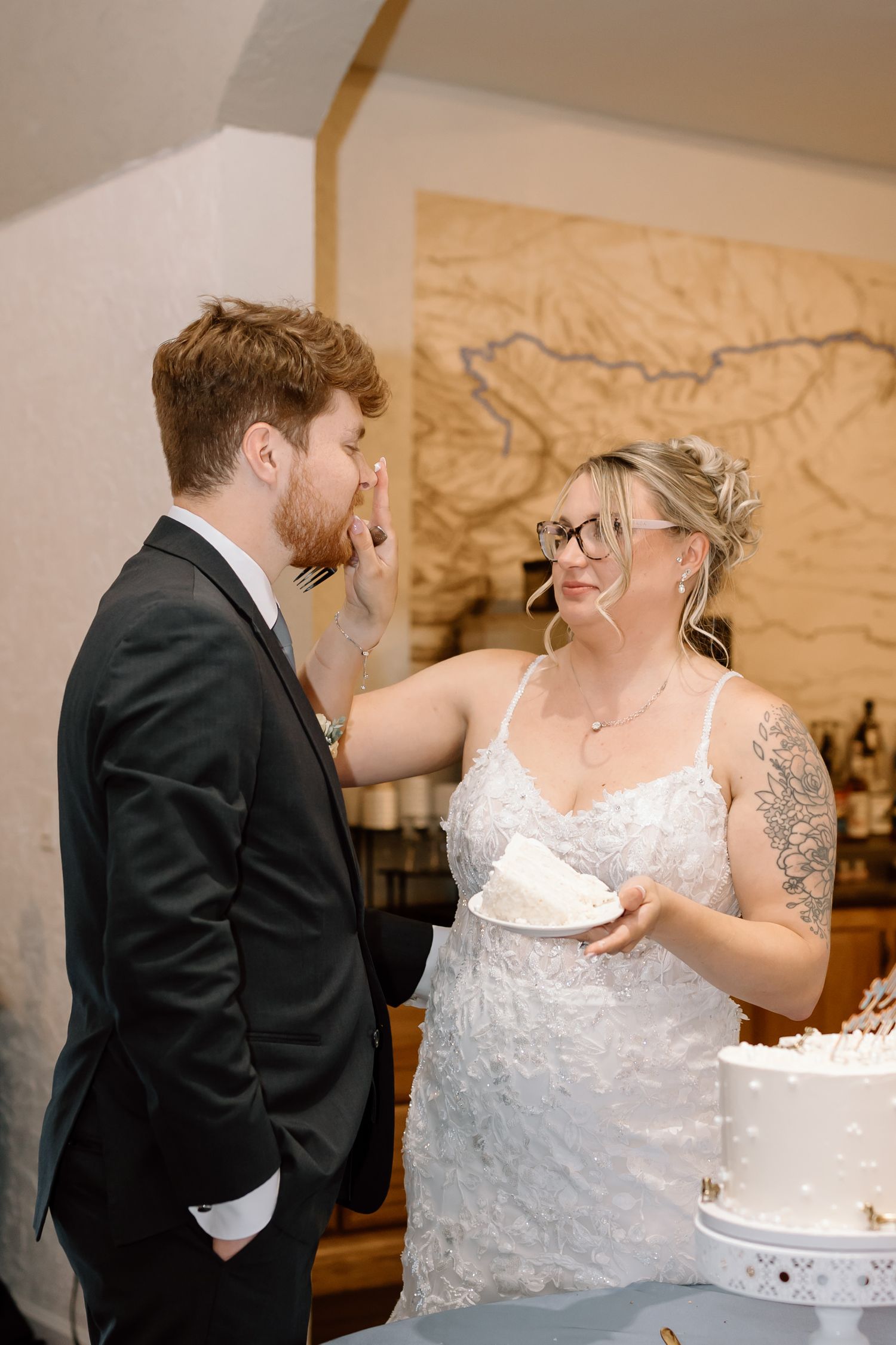 Newlywed couple playfully feeds each other wedding cake during traditional cake cutting ceremony.
