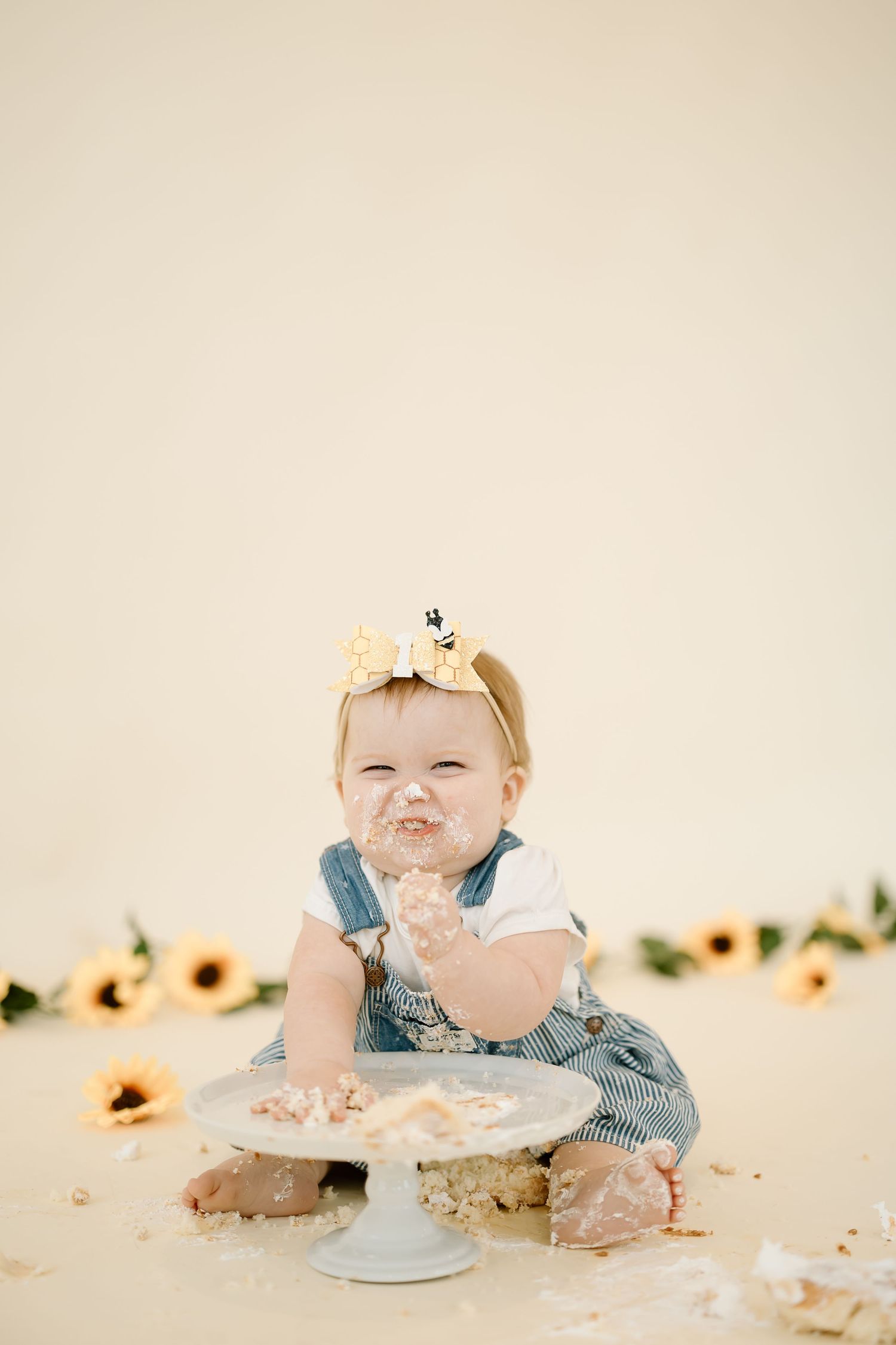 A sequence of four photos showing a baby's cake smash session with a blue outfit and sunflower decorations.