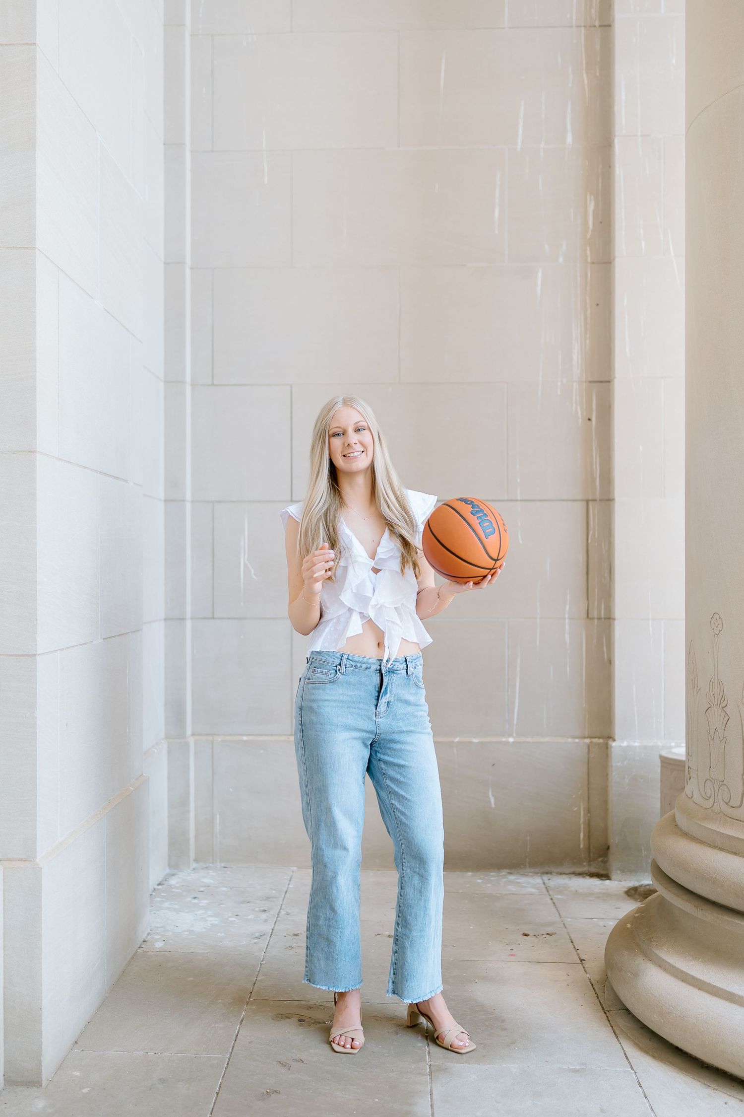 A casual portrait with a basketball and ice cream cone against a light stone wall background.