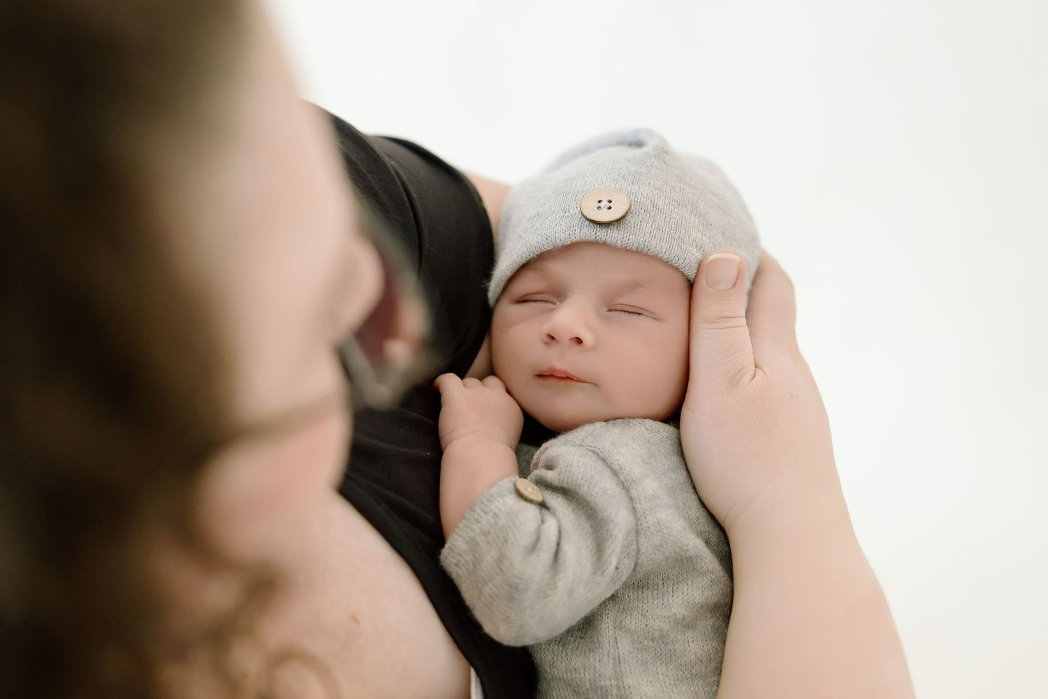 A black and white photo collage showing tender moments between a parent and newborn baby.
