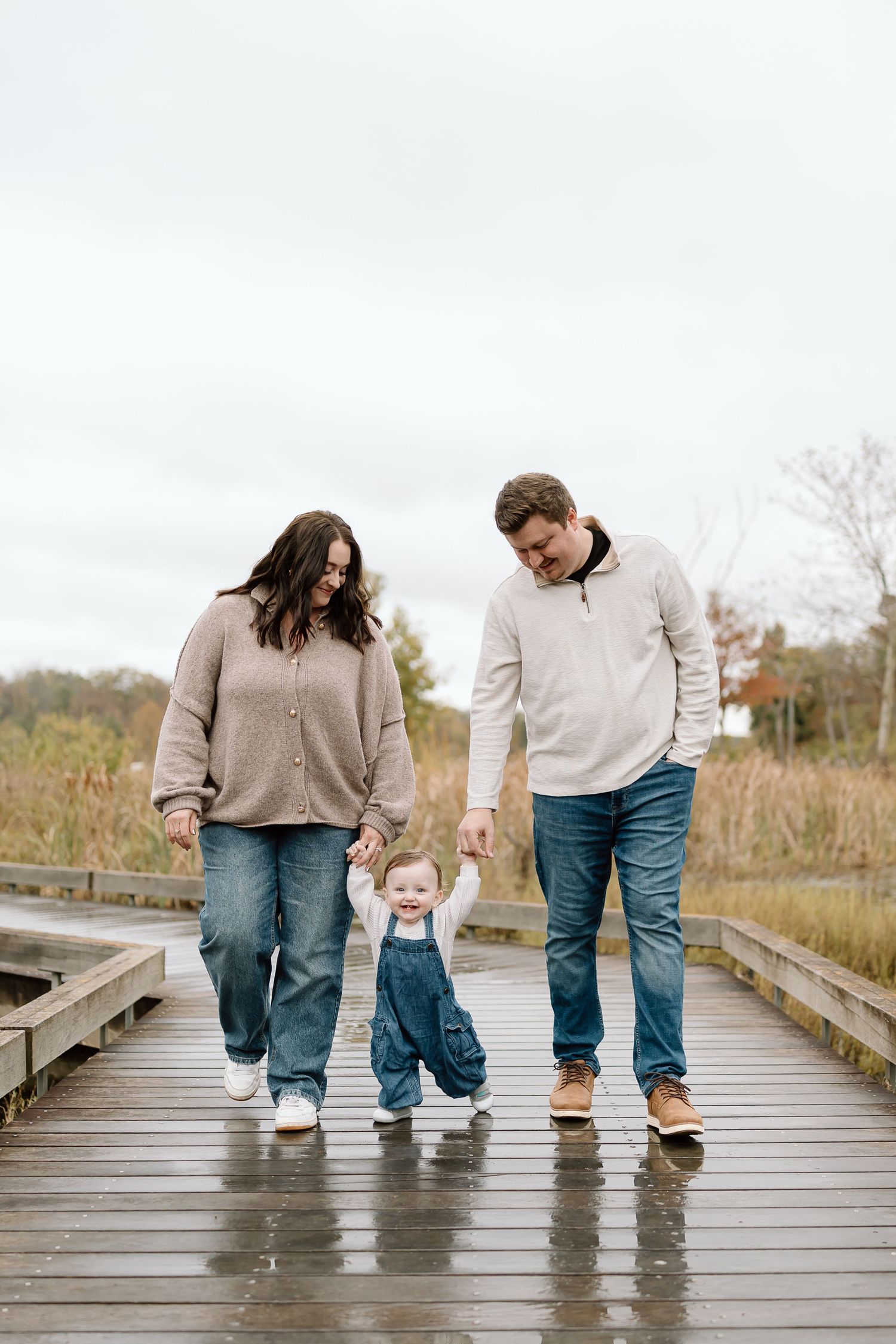 Family walking together on wooden boardwalk in autumn showing their feet and legs in casual attire.