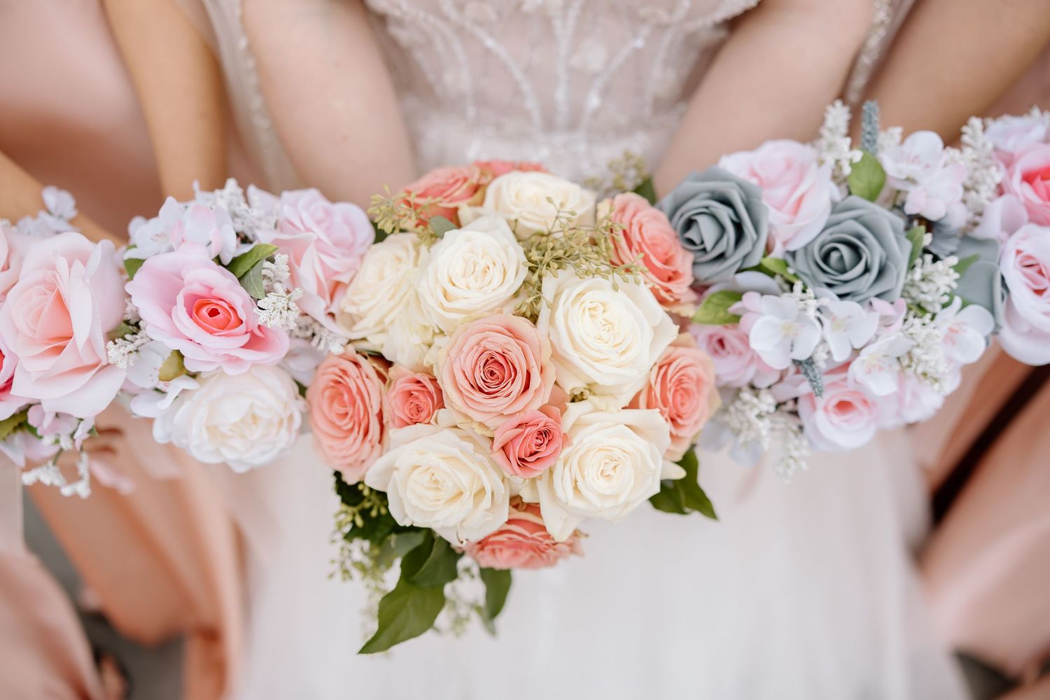 A delicate floral arrangement featuring pink and white roses with soft gray accents creates an elegant wedding display.