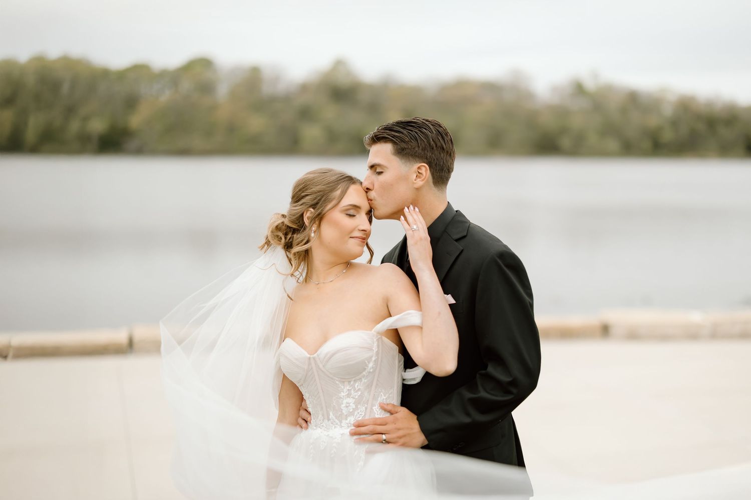 Intimate moment between newlyweds during lakeside portrait session.