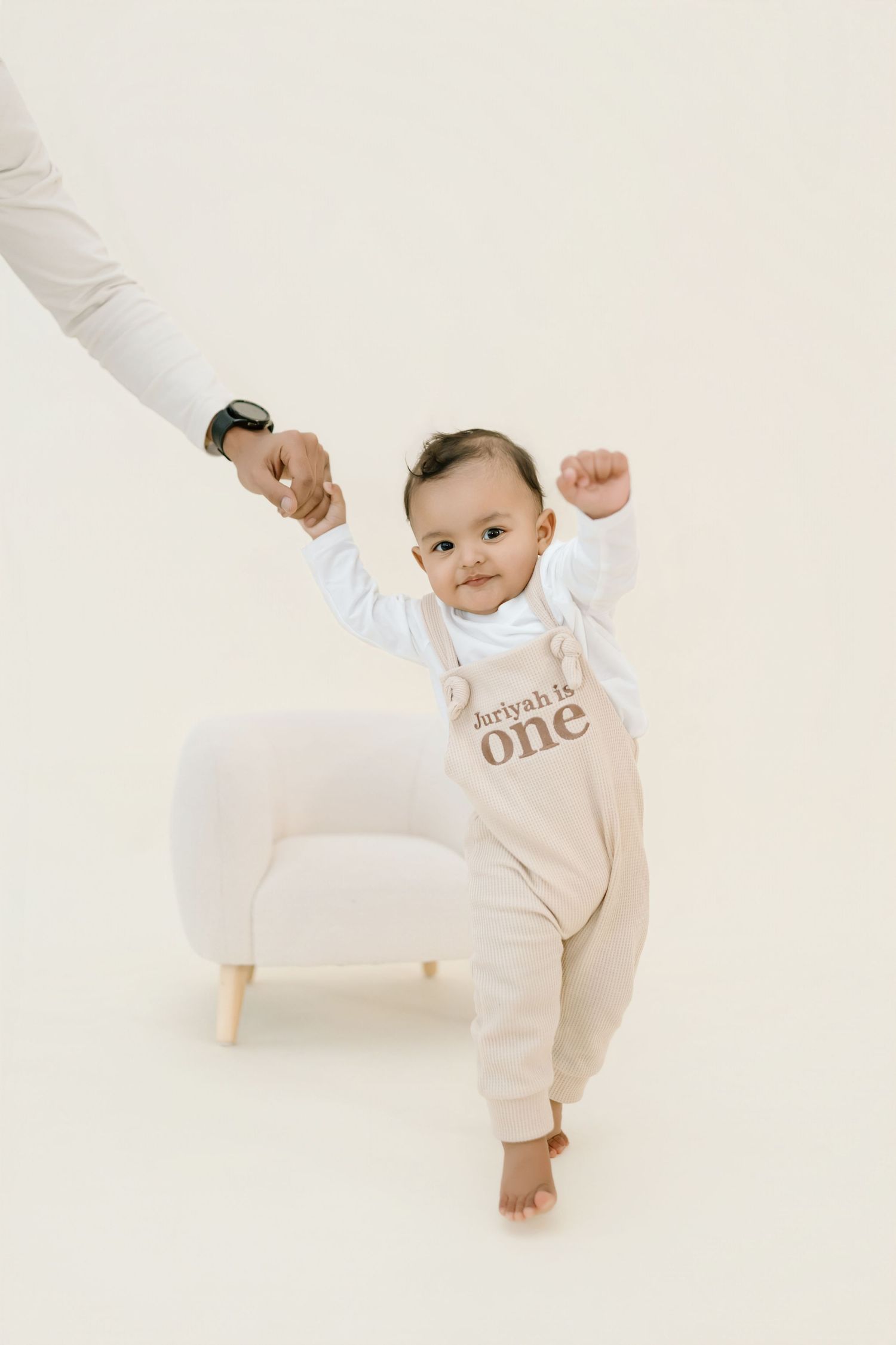 Baby in cream-colored outfit crawls and plays on white background in series of lifestyle photos.