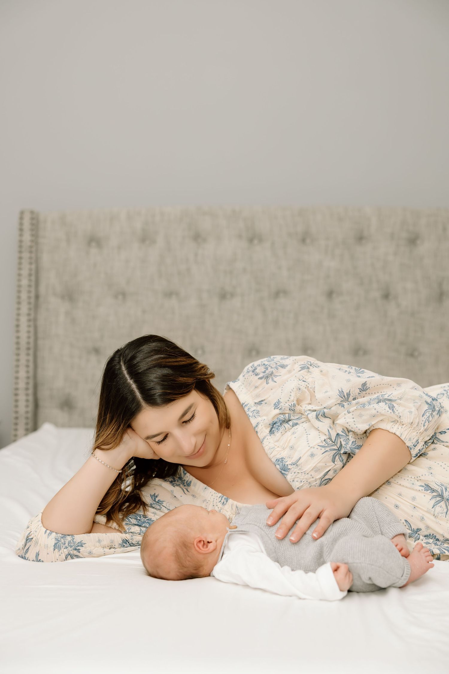 A mother and baby lying on a white blanket in a tender moment captured in a series of connected photos.