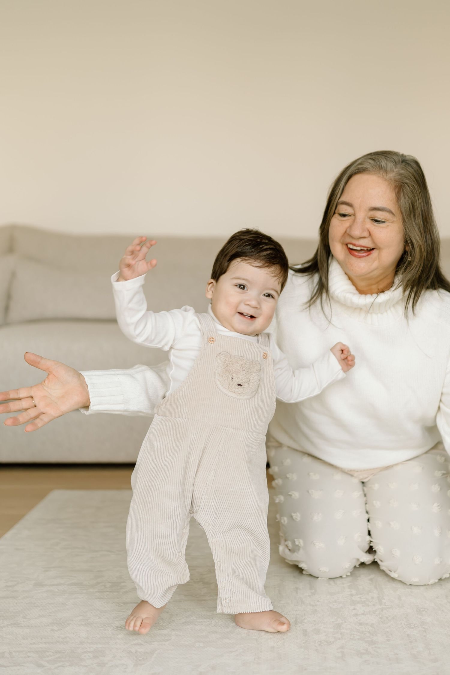 A joyful moment shared between two people in matching white outfits playing and laughing together on a light carpet.