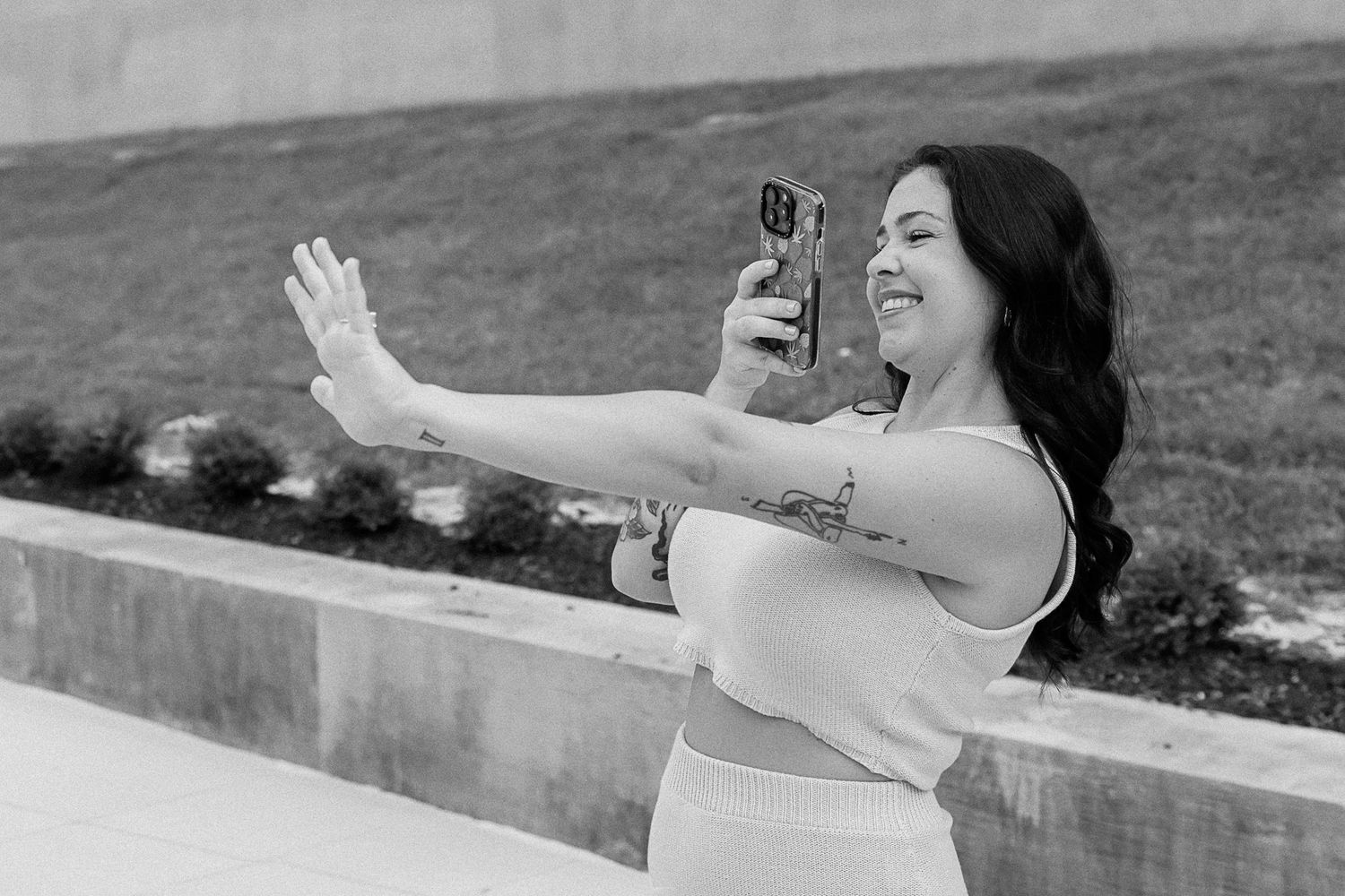 A series of images shows someone taking selfies with a phone while sitting on an outdoor ledge.