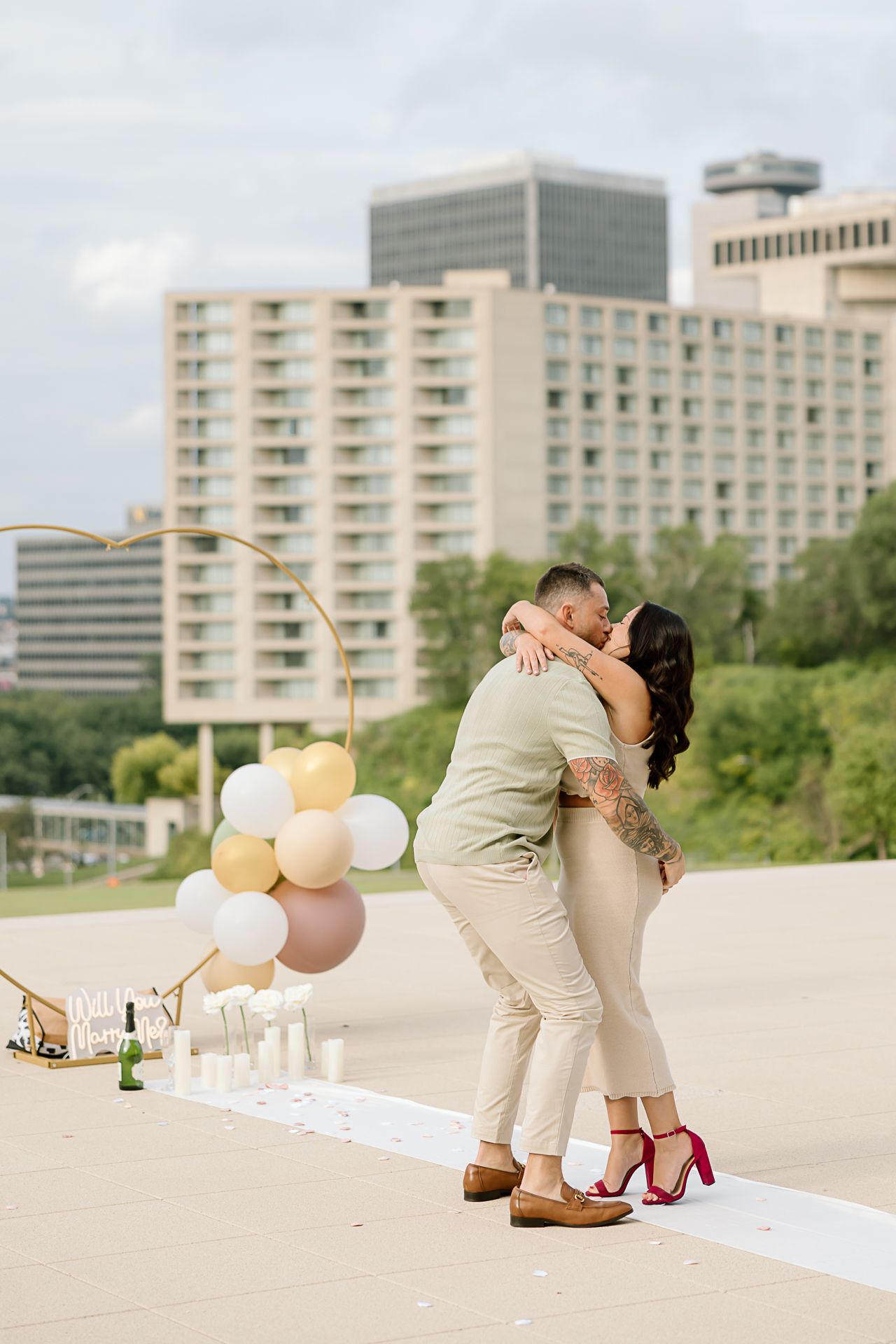 A romantic rooftop scene with balloons and white decor against an urban skyline.