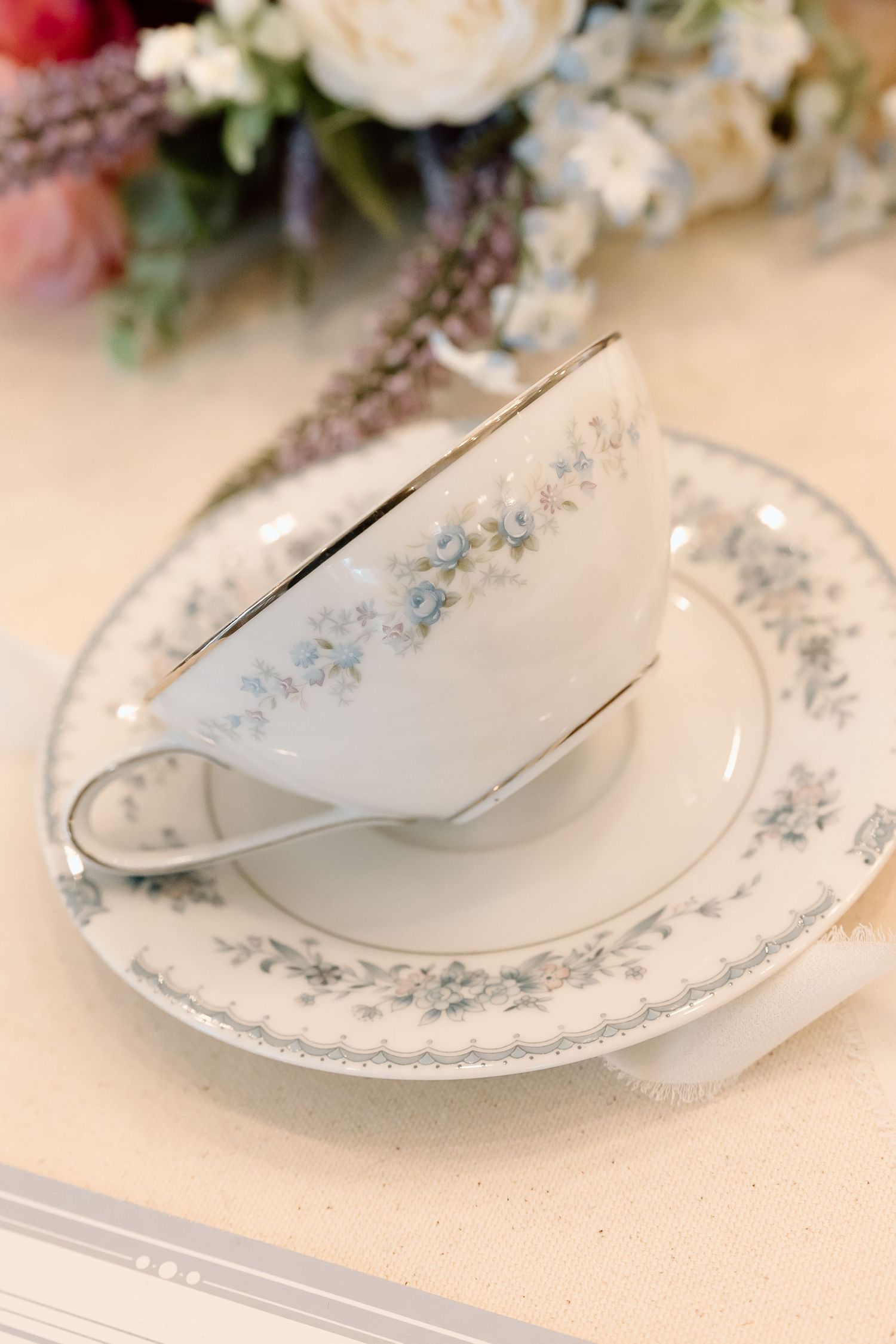 Elegant vintage china plates with delicate blue floral patterns arranged in a row on a cream-colored surface.