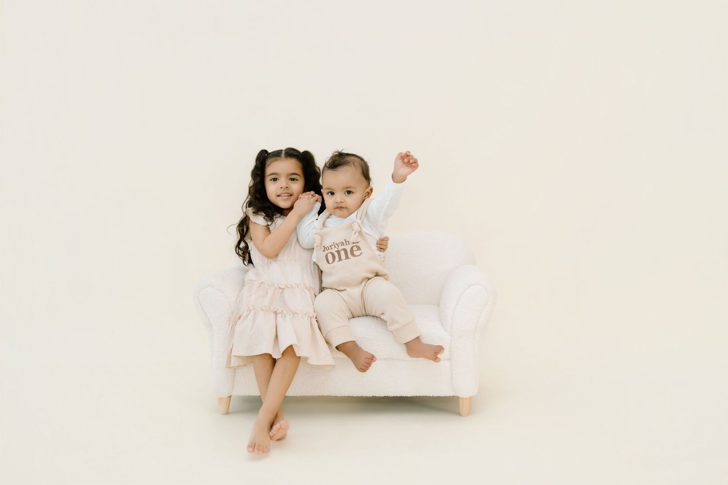 Children in white outfits sitting together on a white background.