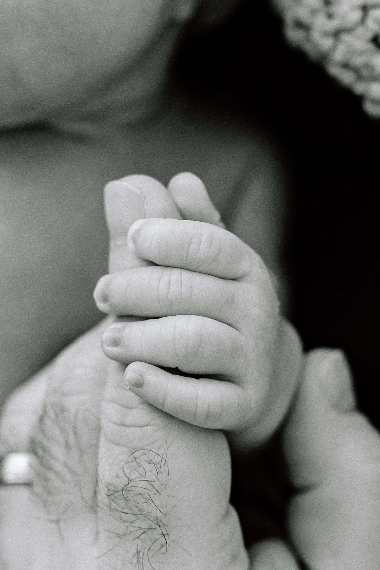 Close-up black and white photo of two hands gently touching and intertwining against a soft background.