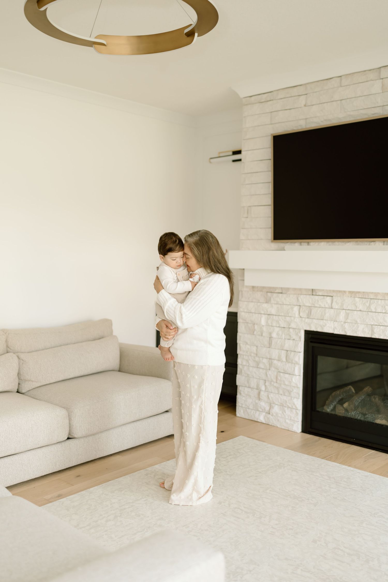 Modern living room interior with white brick fireplace, cream sofa, and warm lighting from circular pendant lamps.