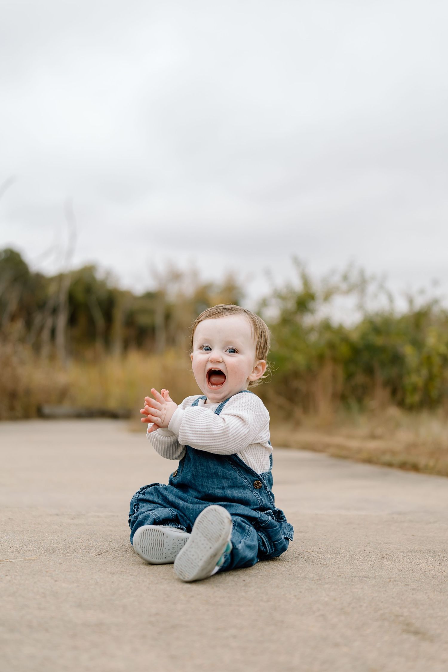 A sequence of photos shows a baby in denim overalls sitting on a concrete path while expressing different emotions.