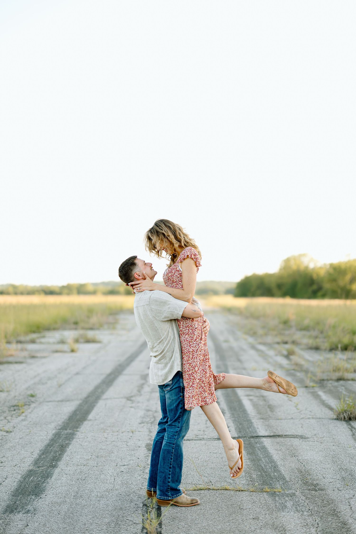 A couple shares a romantic moment on a dirt road during sunset, spinning and embracing in a series of joyful poses.