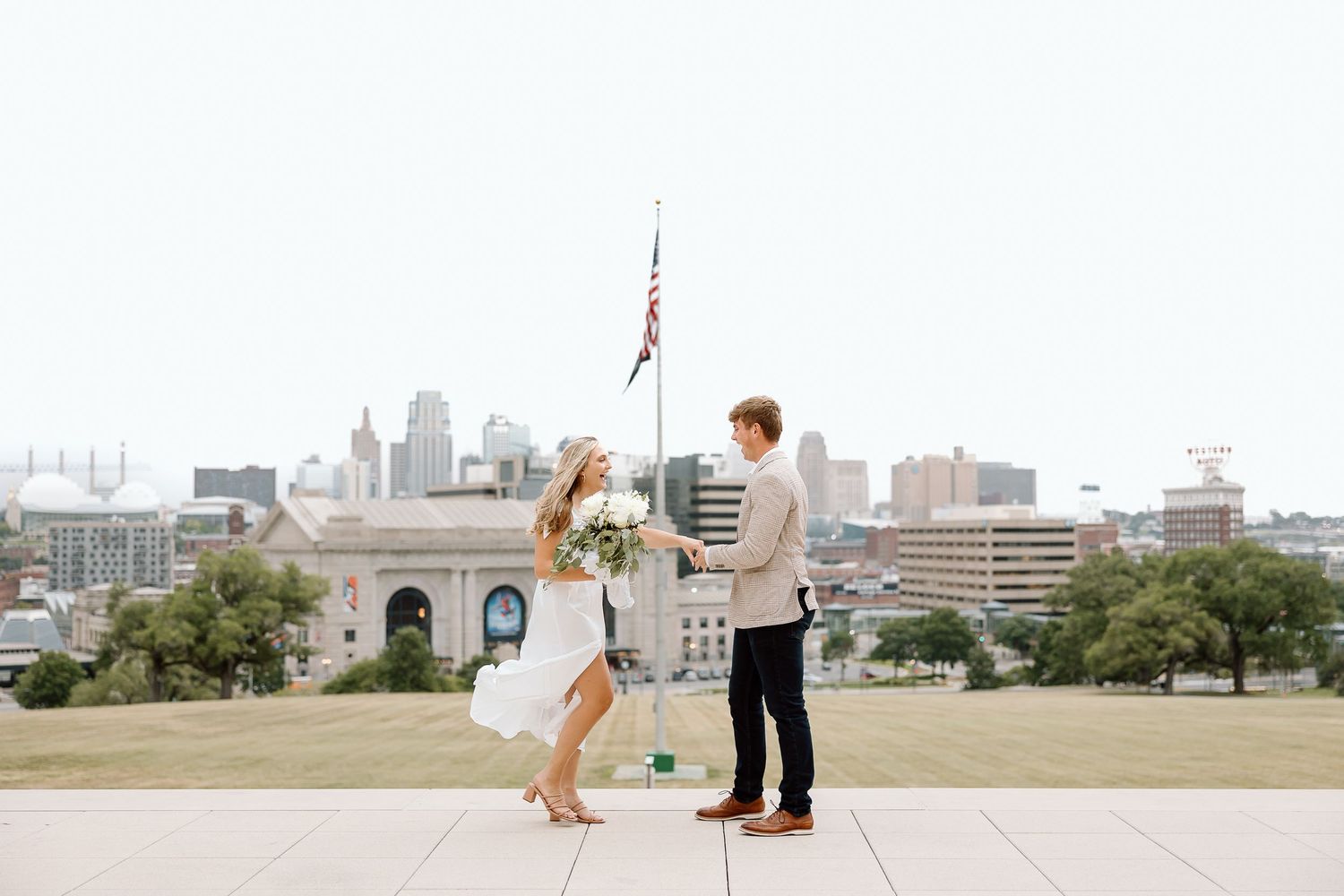 A couple stands together on a rooftop overlooking a city skyline during a romantic moment.