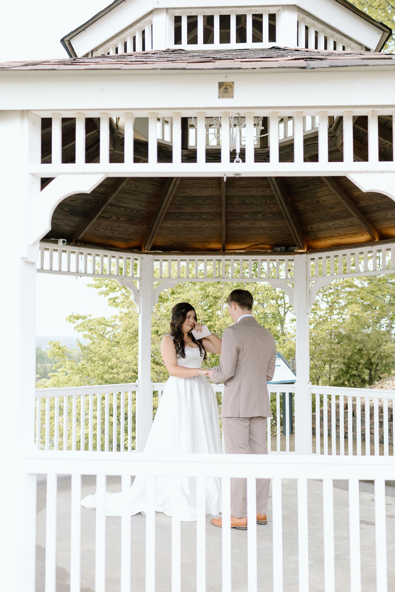 Elegant white gazebo decorated for a romantic outdoor wedding ceremony with white railings and natural surroundings.