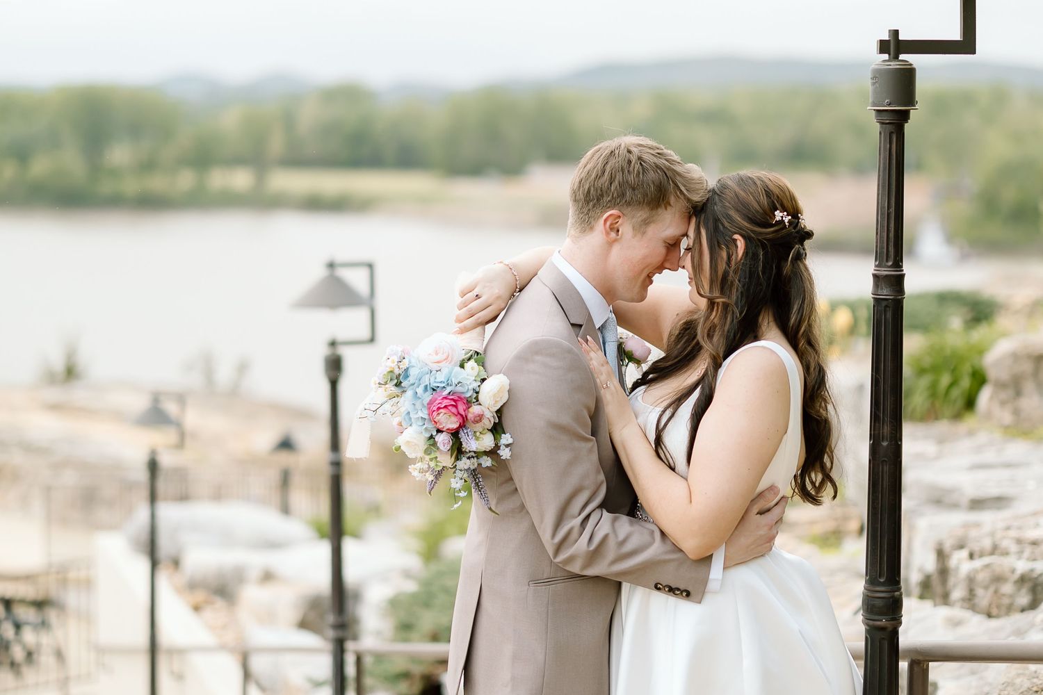 Romantic wedding couple embraces in outdoor setting with rustic decor and natural lighting.