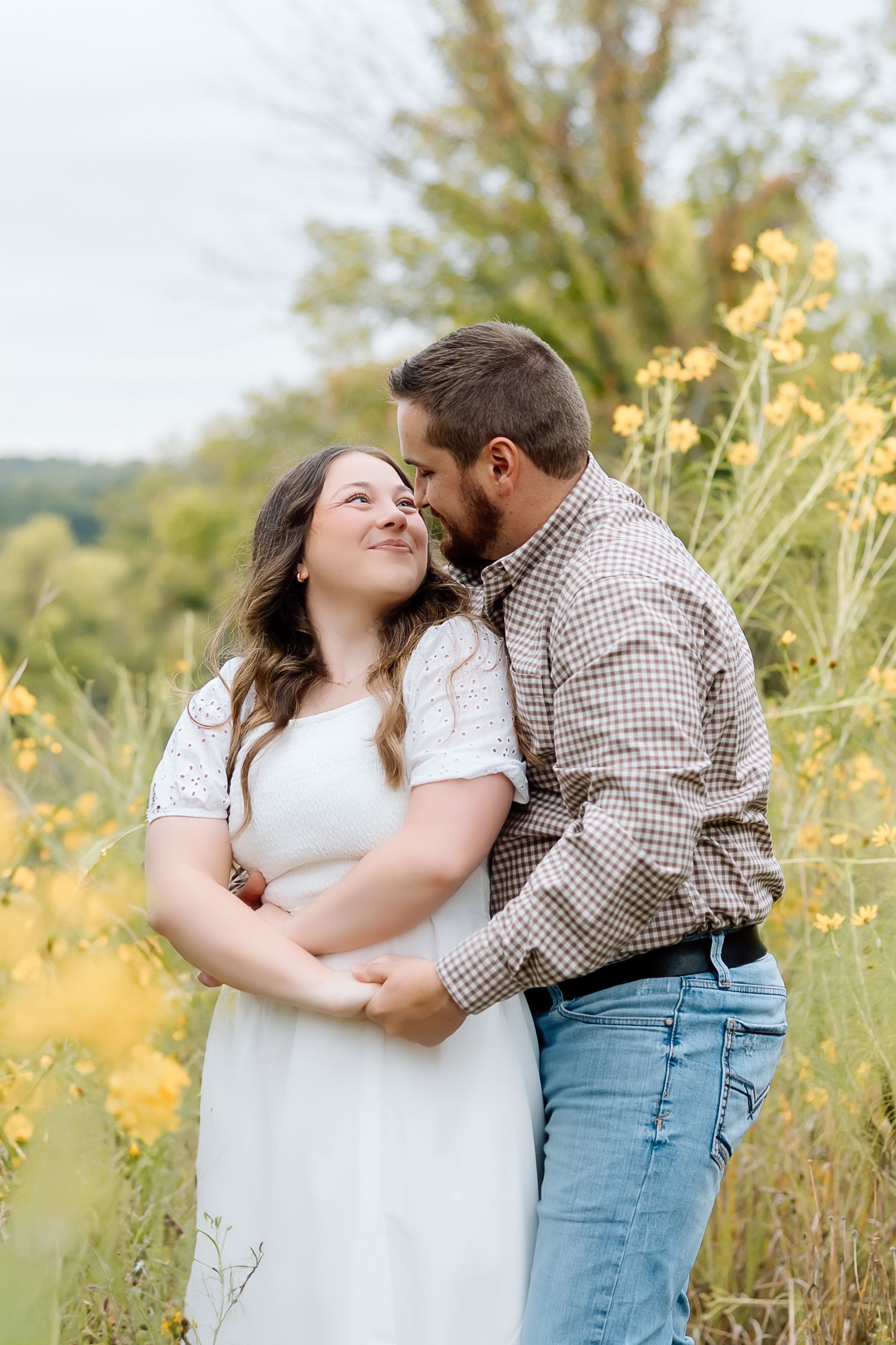 A couple shares a tender moment in a golden meadow with wildflowers.