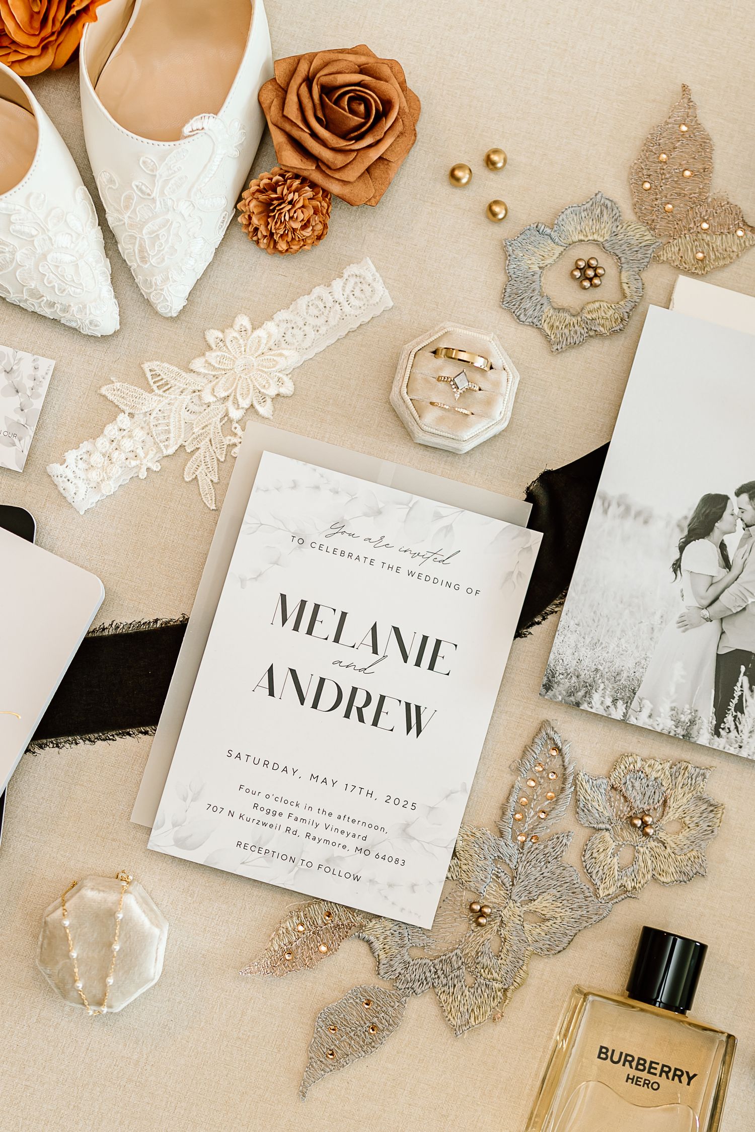 Elegant wedding invitations and accessories arranged on beige background with floral details and gold accents.