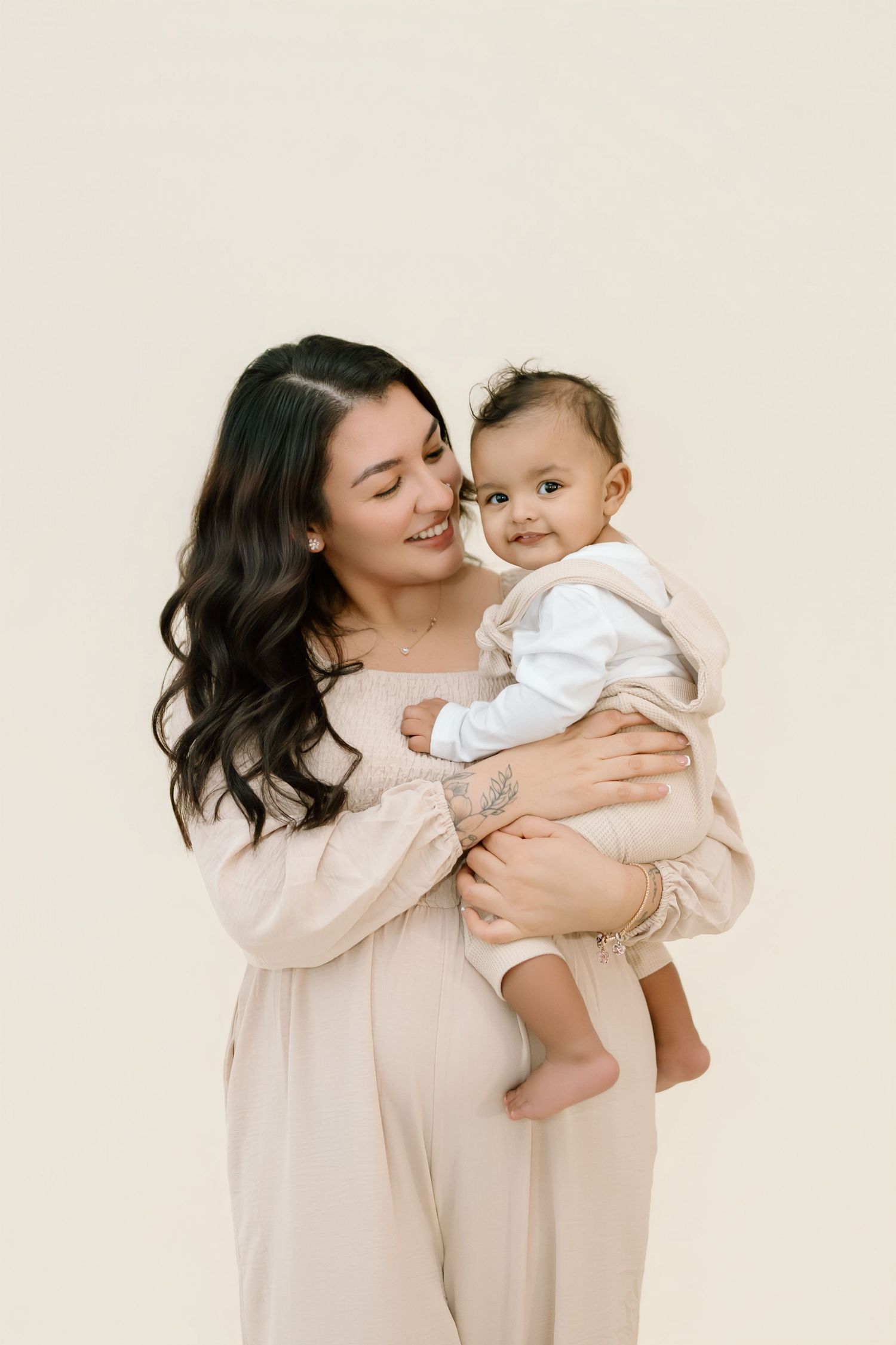 A tender moment captured in a series of four photos showing a parent and baby in matching beige outfits embracing and smiling.