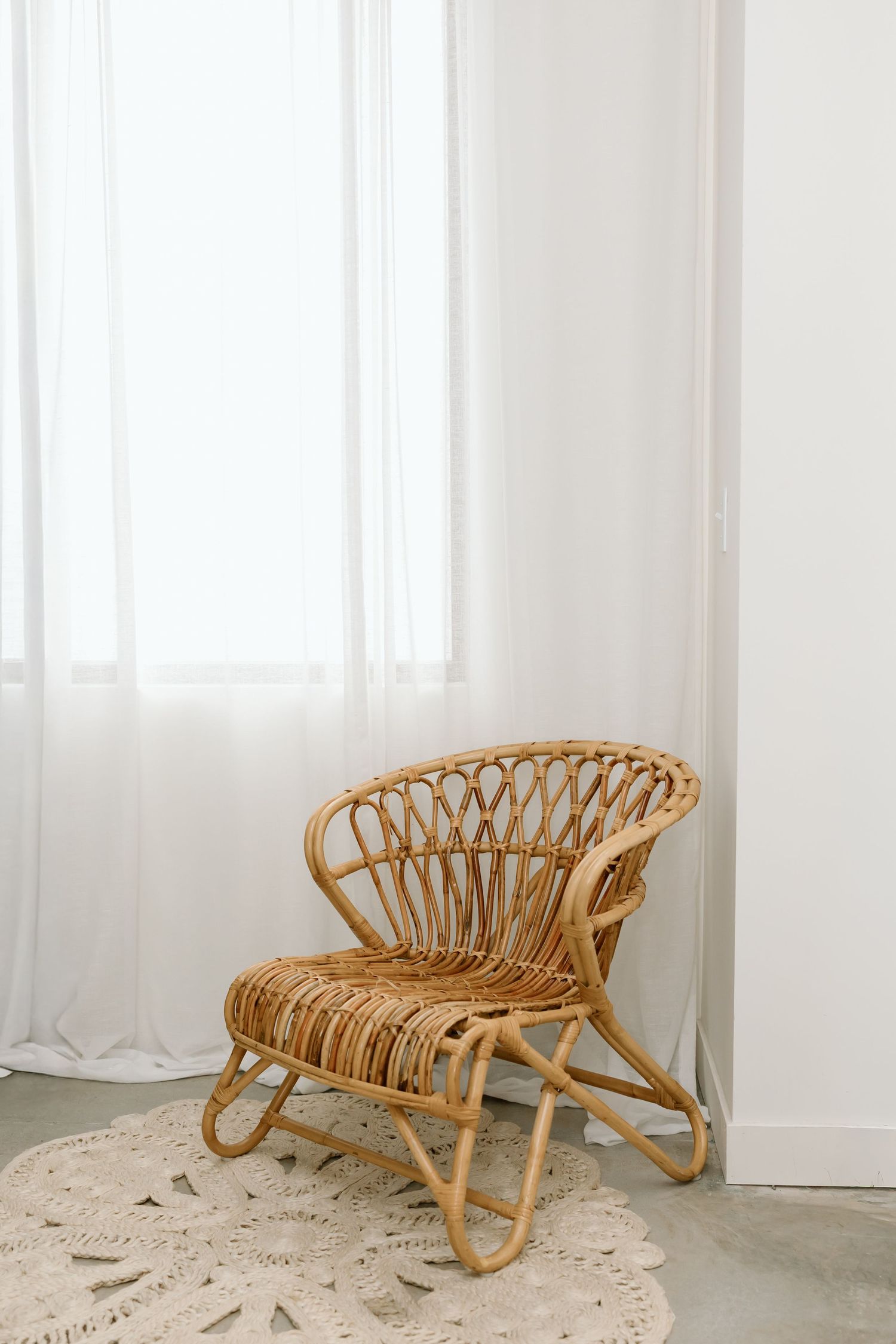 Vintage rattan bamboo chaise lounge with curved design and striped cushions in a bright minimalist room.