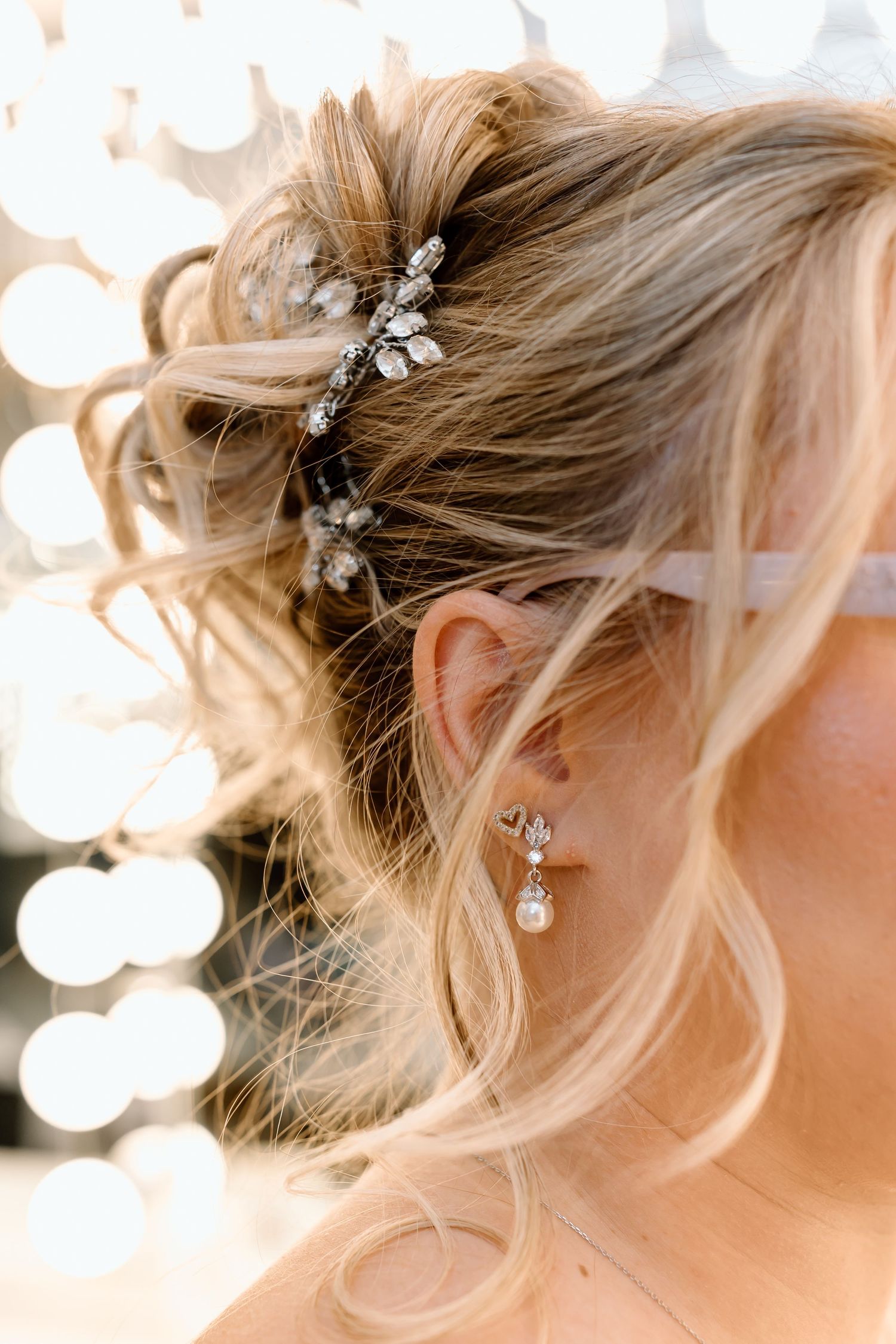 Close-up view of an elegant bridal hairstyle with crystal hair accessories and soft blonde waves.